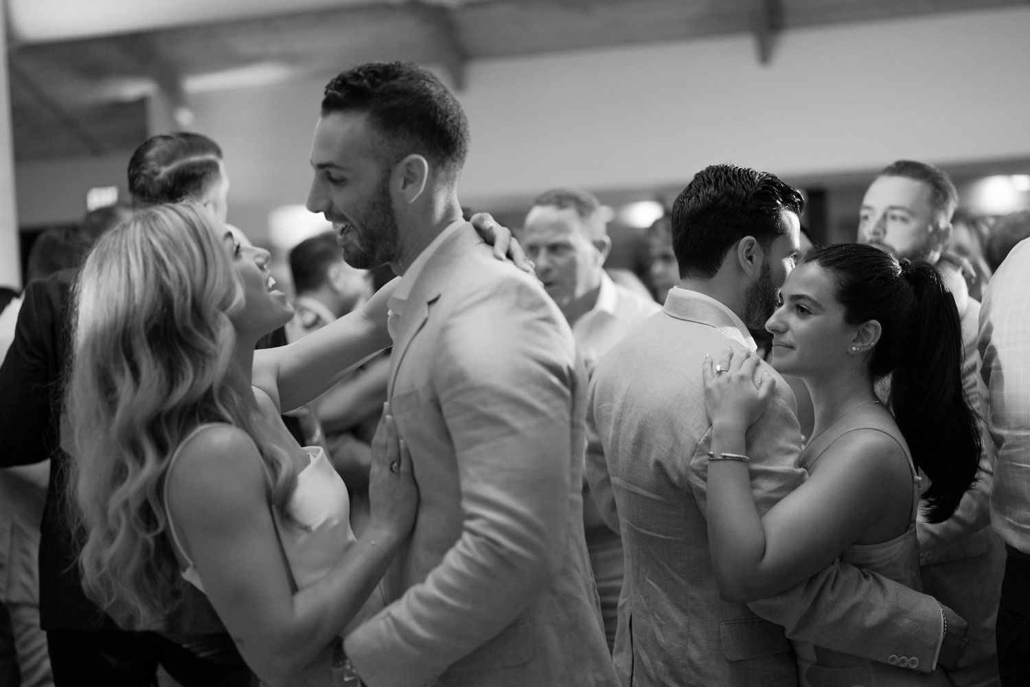 Wedding reception guests dancing and embracing on a crowded dance floor.