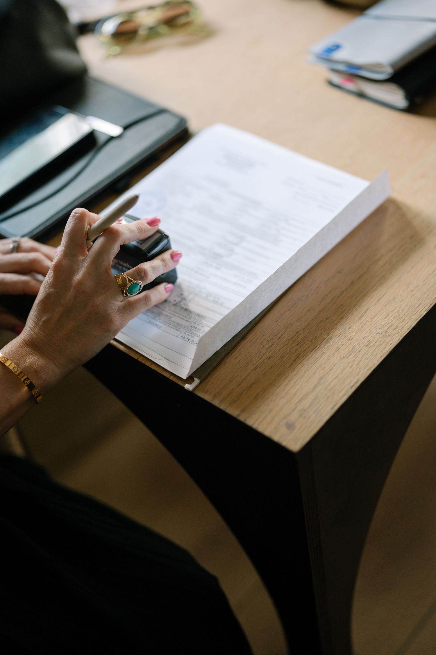 Close-up of hands with painted nails turning pages in a book on wooden desk.