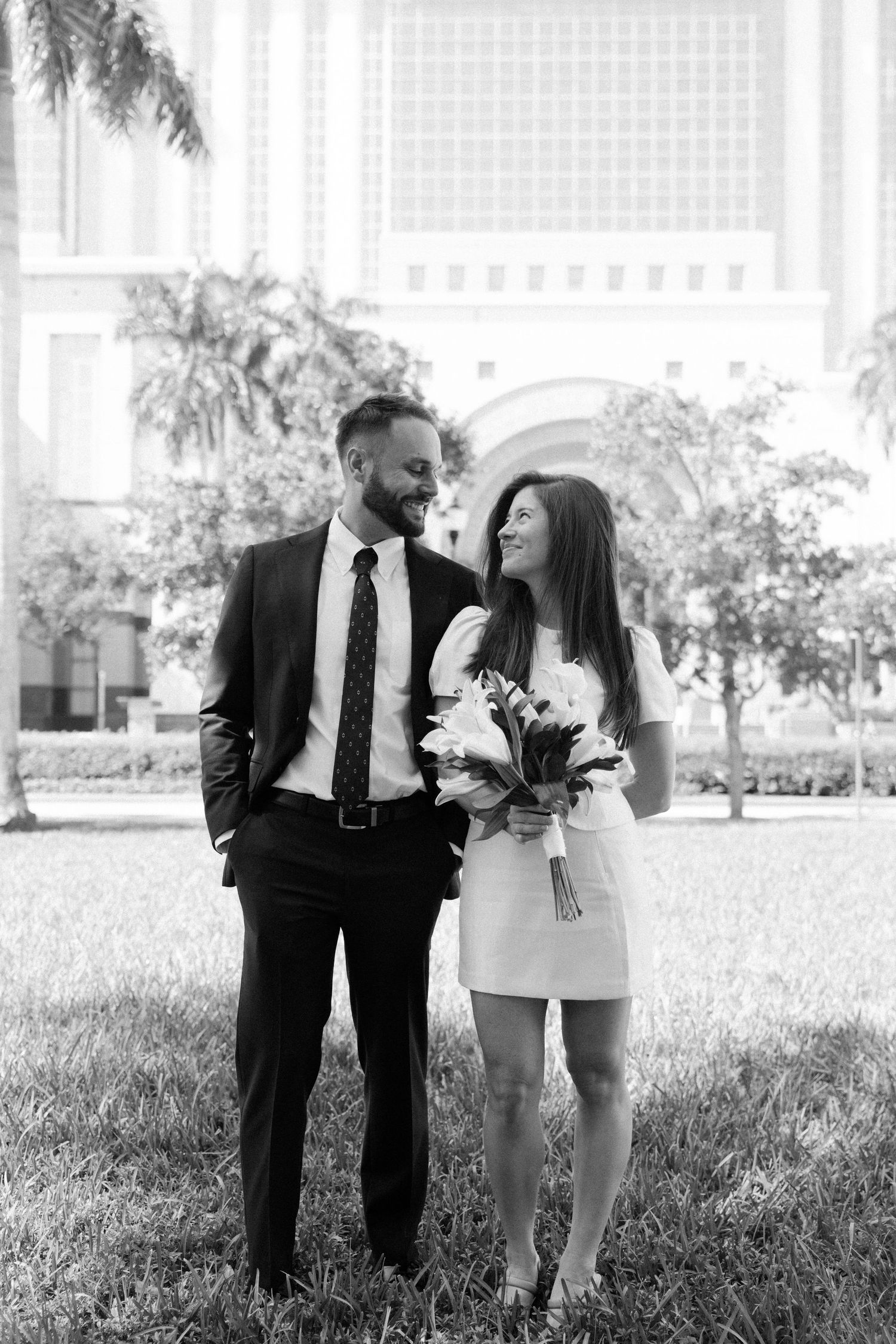A romantic couple shares tender moments in a garden setting wearing formal attire.