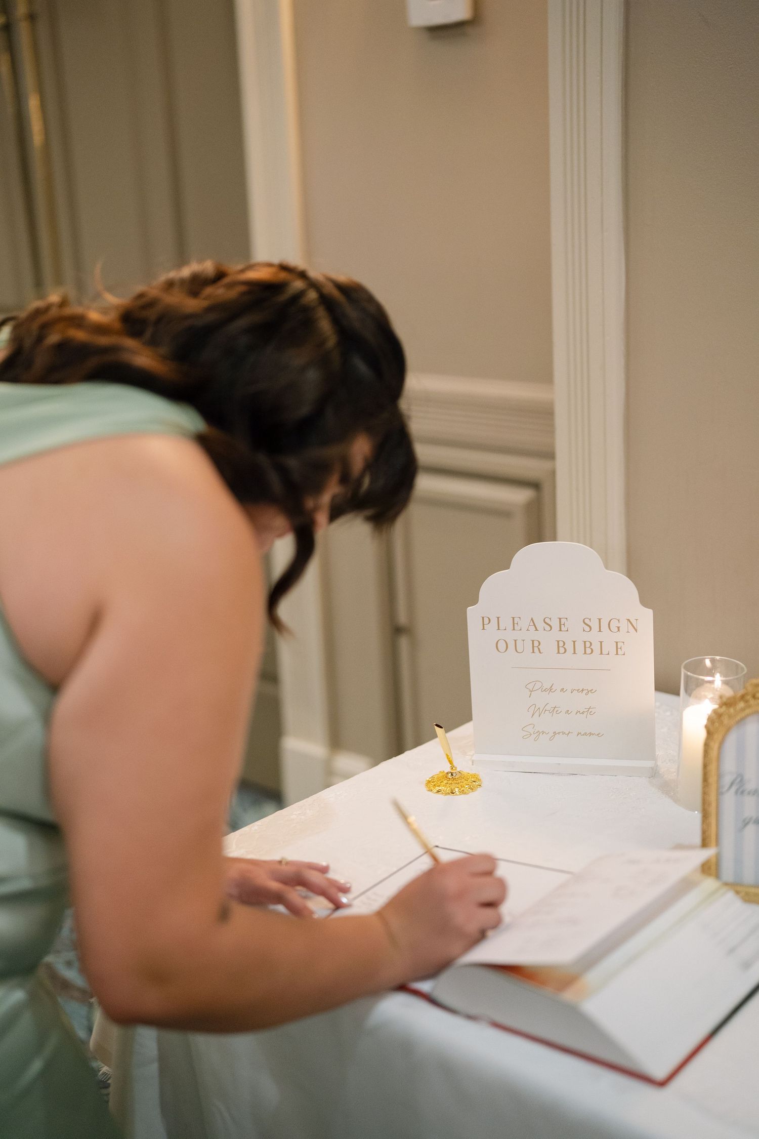 Wedding guest book and signing table with elegant white decor and candle.