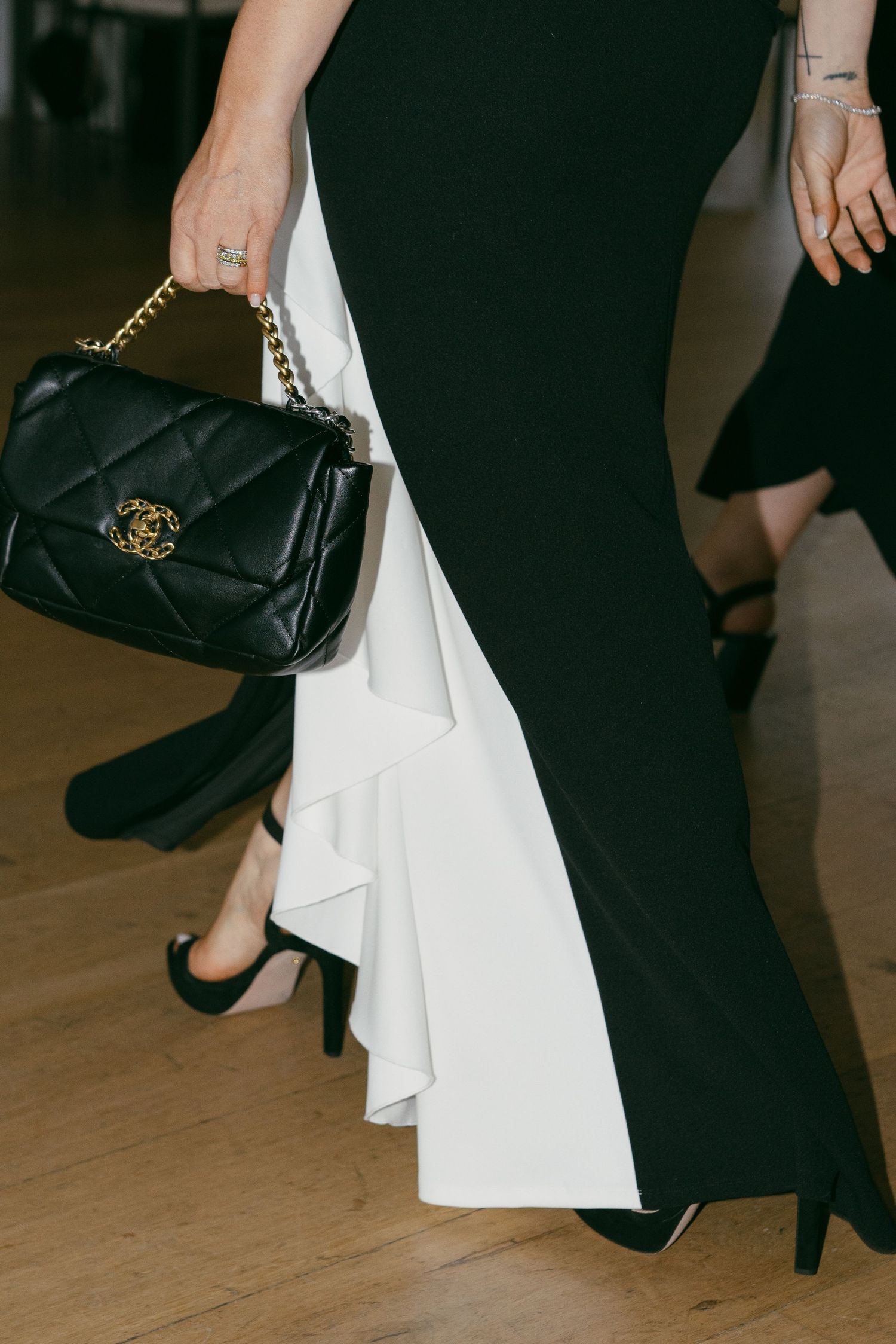 Detail shots of black formal shoes and designer handbags on a wooden floor.
