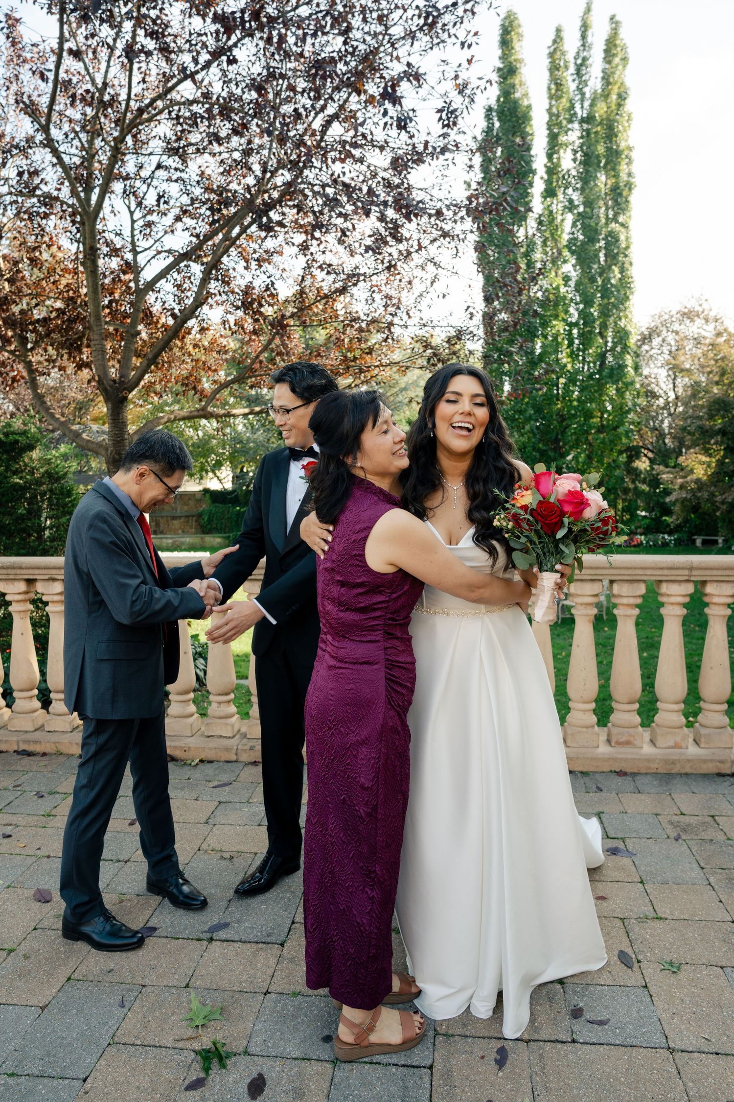 Wedding party celebrating and laughing together on an outdoor stone patio.