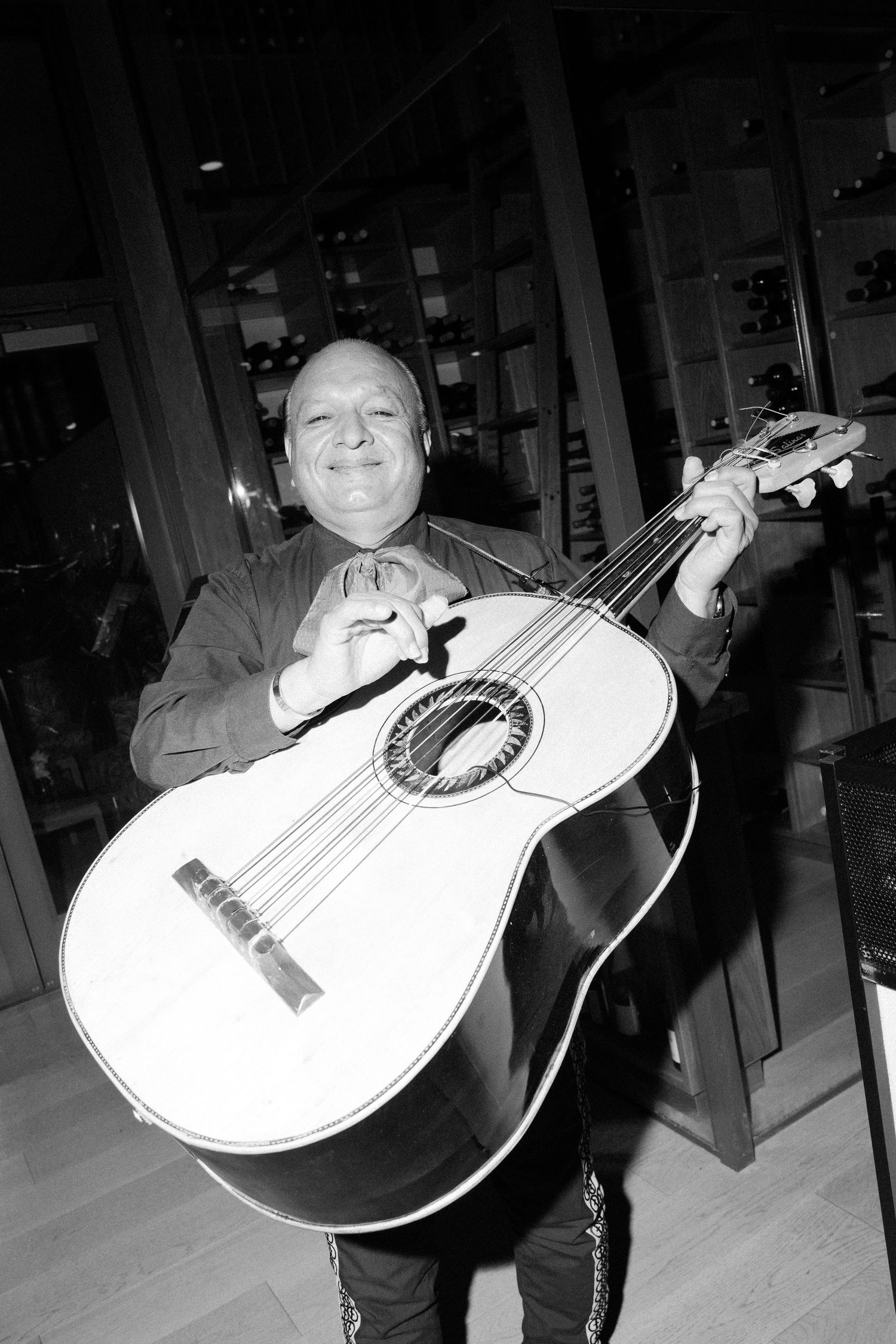 Black and white photos of someone playing an acoustic guitar at an indoor event.
