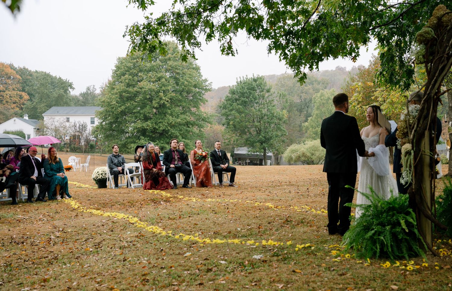 People gather in a park during autumn with fallen leaves scattered across the ground.