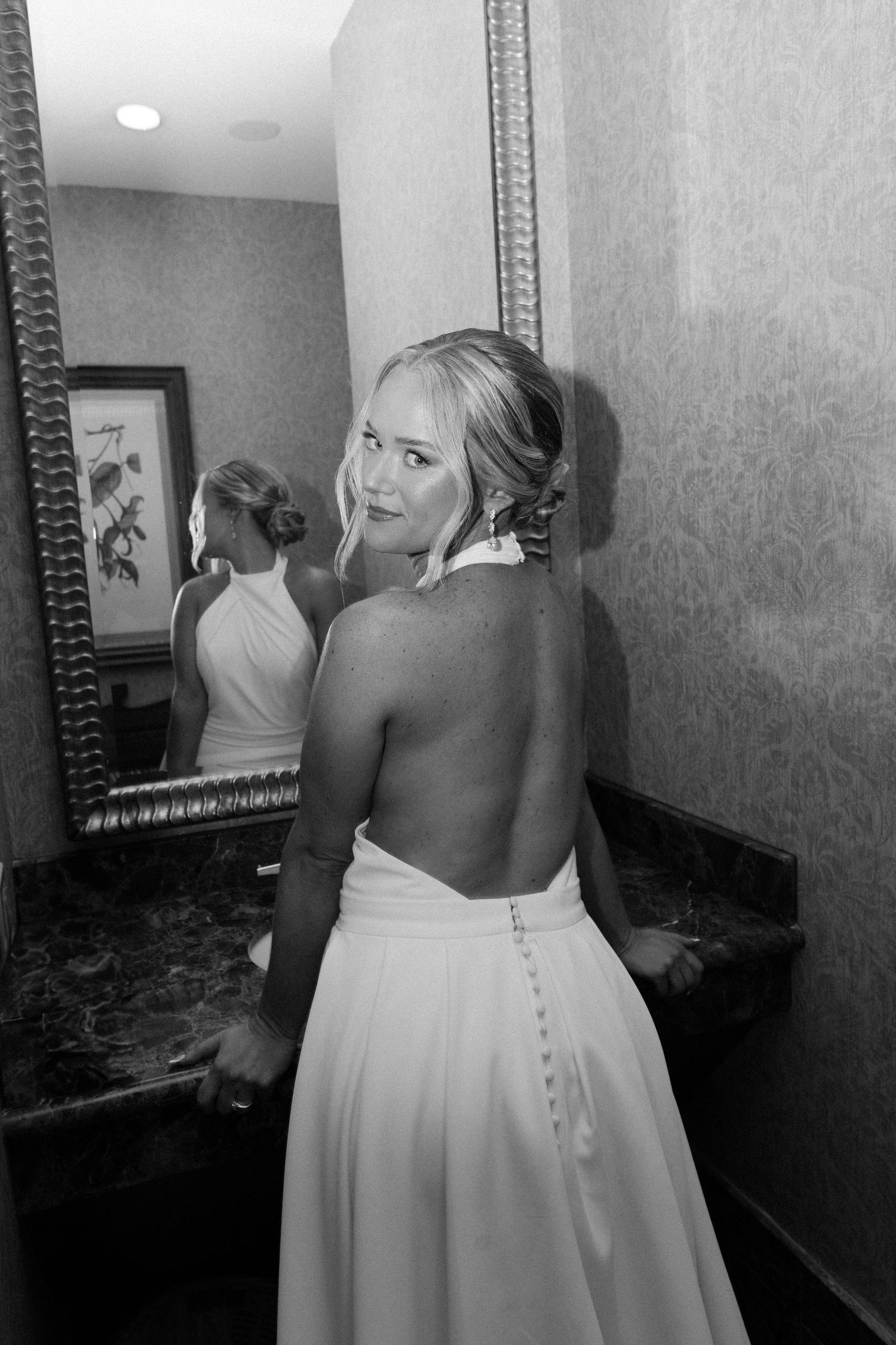 Black and white photo showing back of elegant wedding dress with button details and mirror reflection.