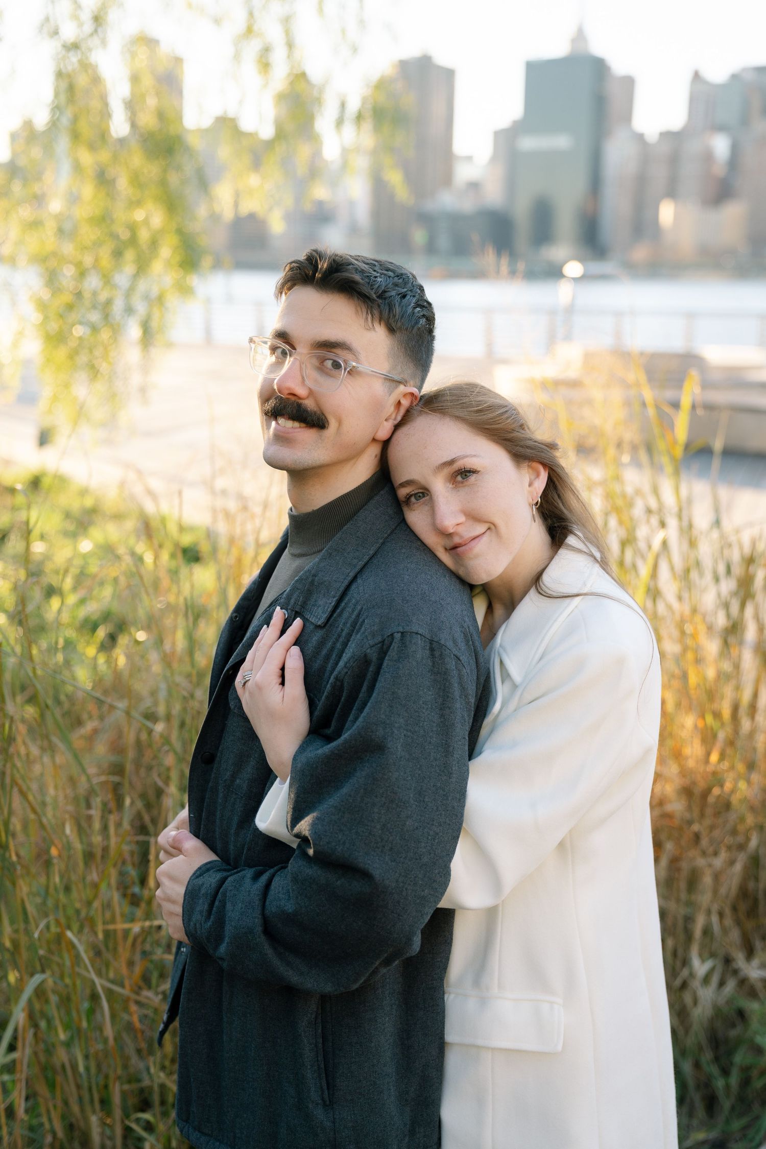 Couple in black and white outfits sharing tender moments against an autumn landscape.