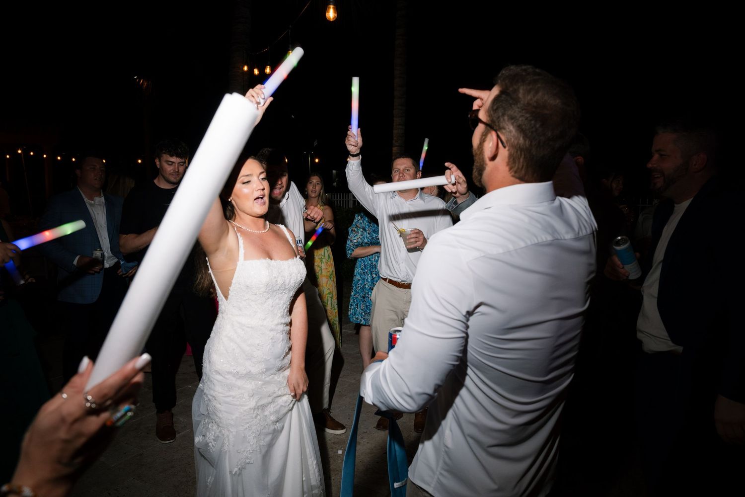 Wedding couple dances together during dark reception with glowsticks.