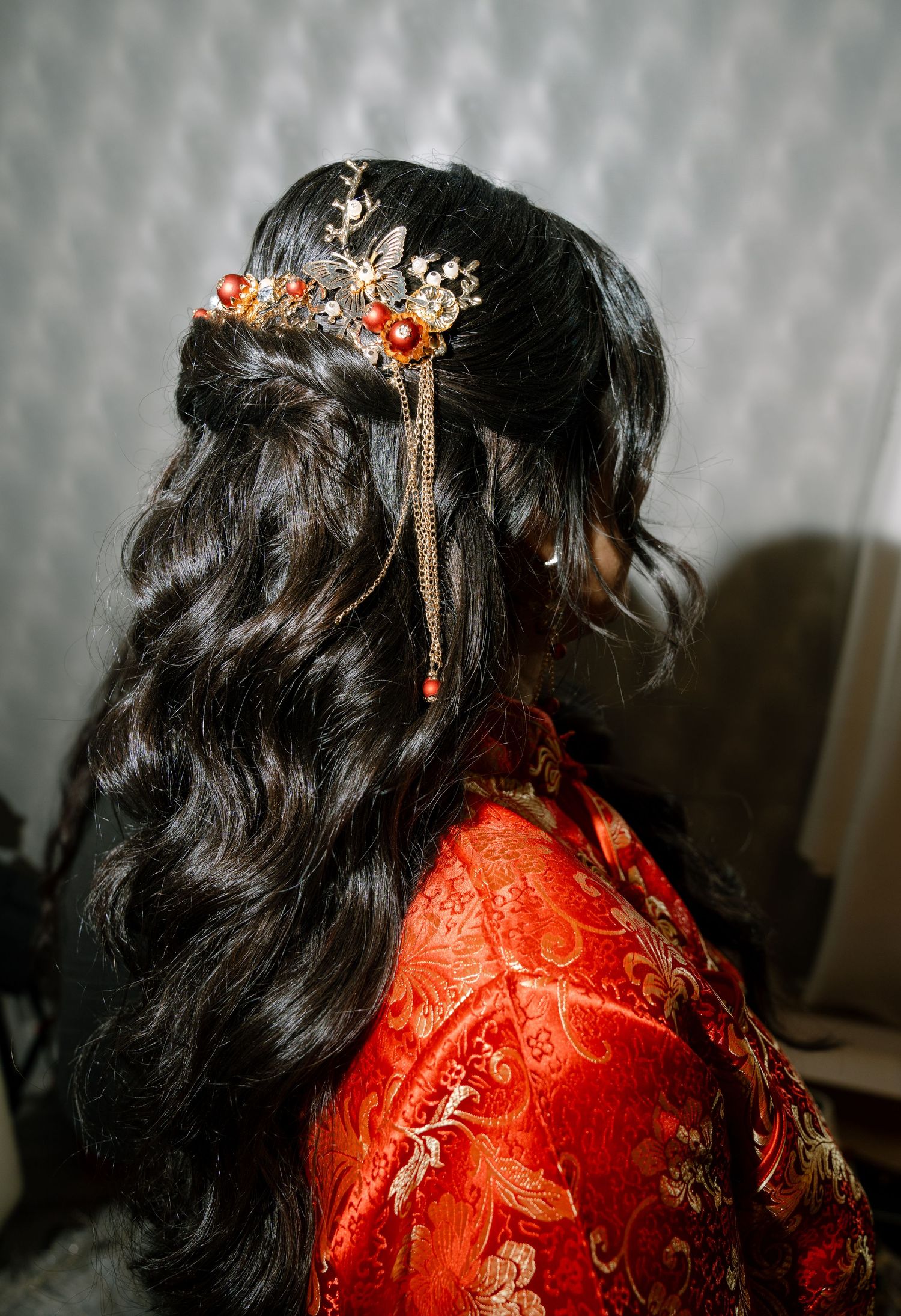Close-up details of ornate red traditional Chinese wedding dress with gold embroidery and hair accessories.