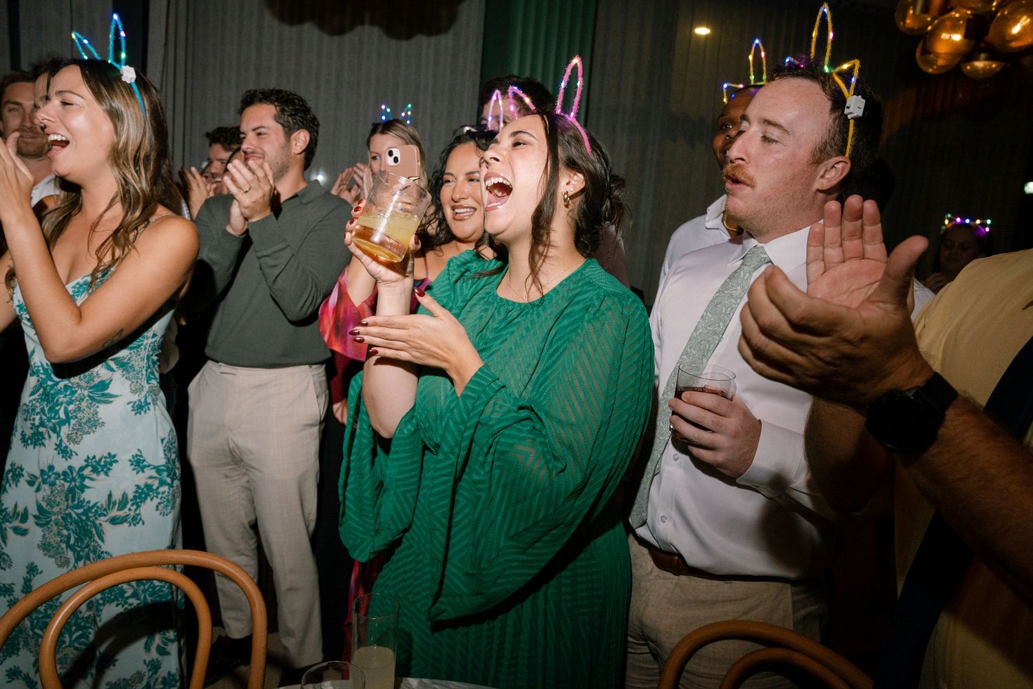 Party guests dancing and celebrating at a lively indoor event with atmospheric lighting.