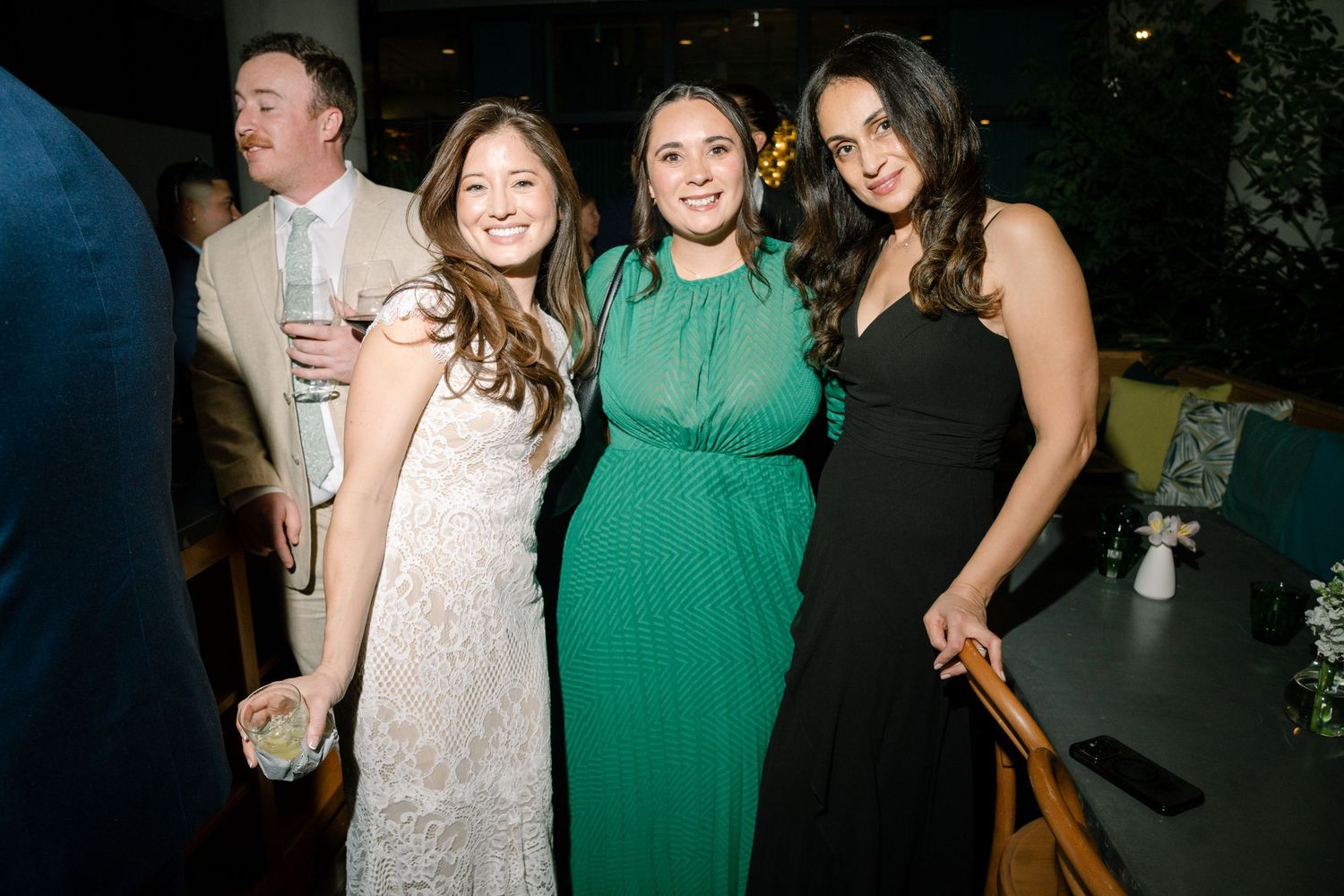 Wedding guests in formal attire gather for a celebratory photo at an evening reception.