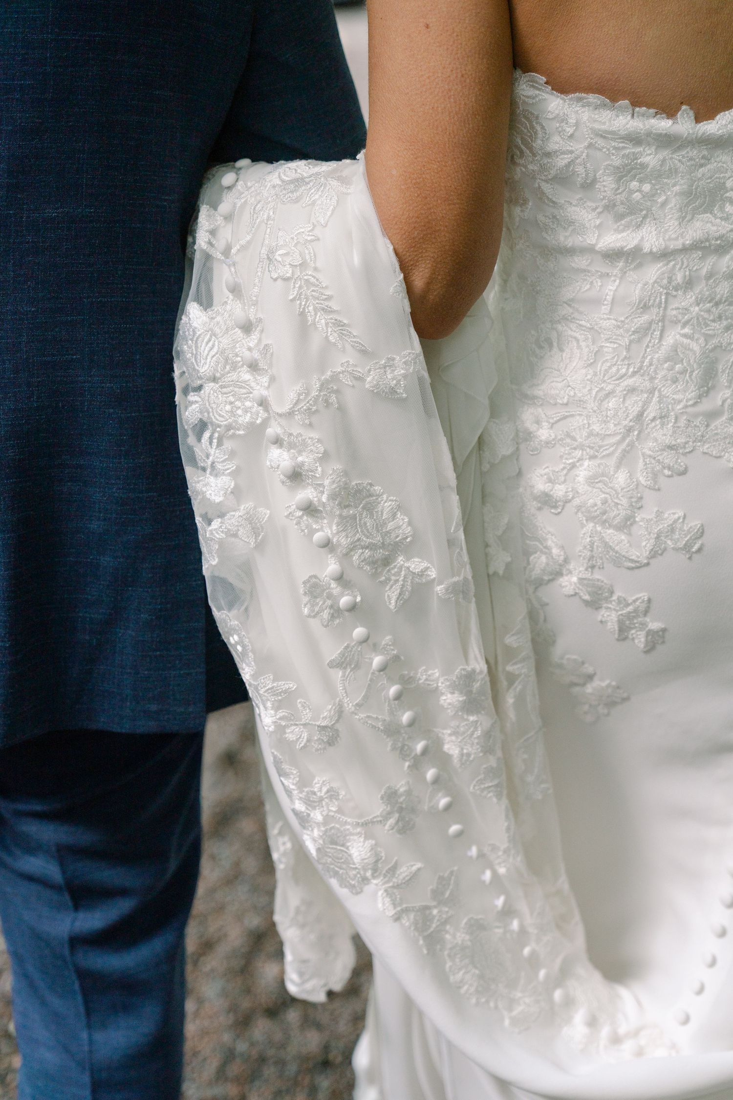 Close-up detail of intricate lace pattern on a white wedding dress.