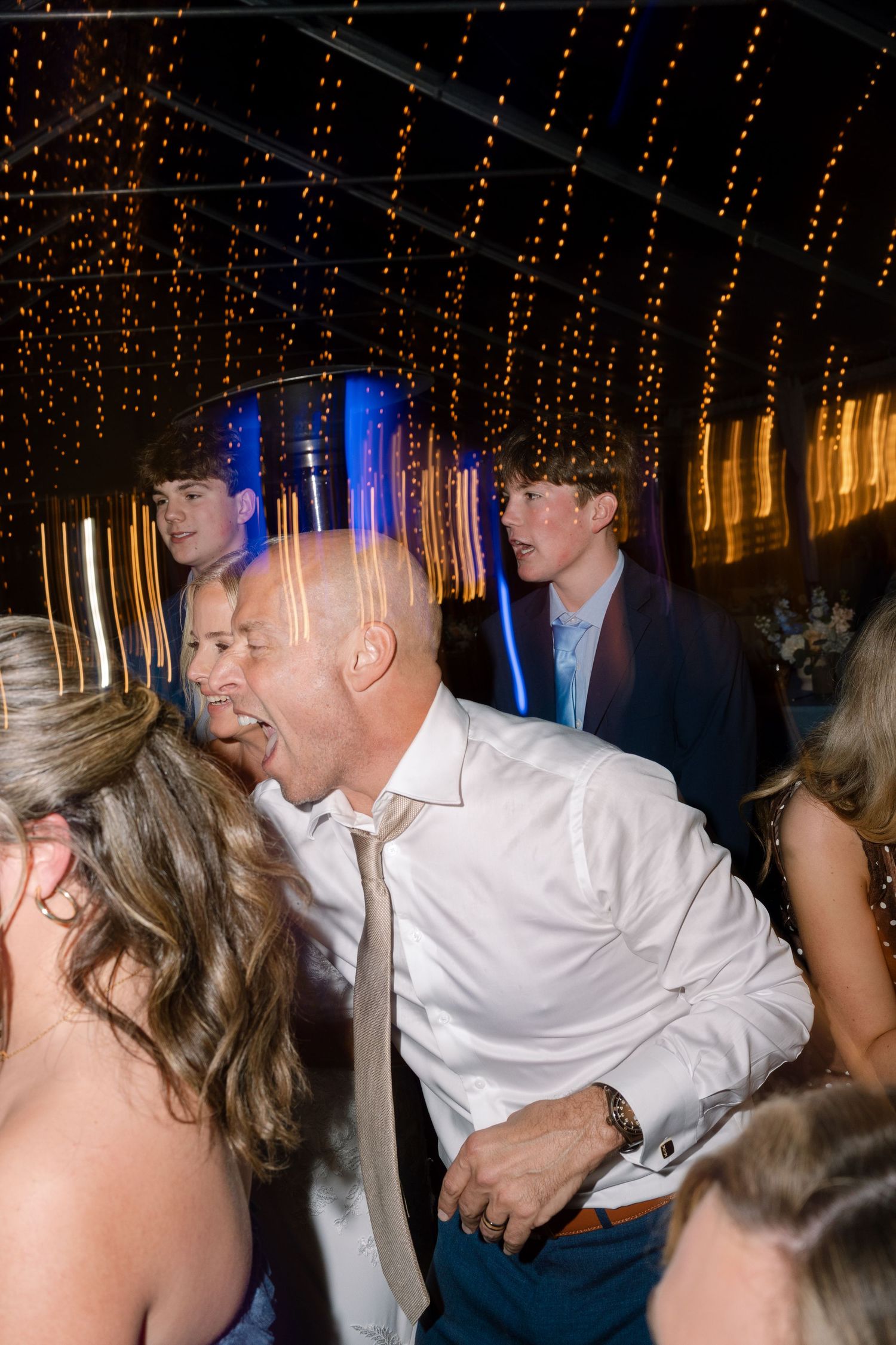 Wedding reception dance party with string lights creating a magical atmosphere.