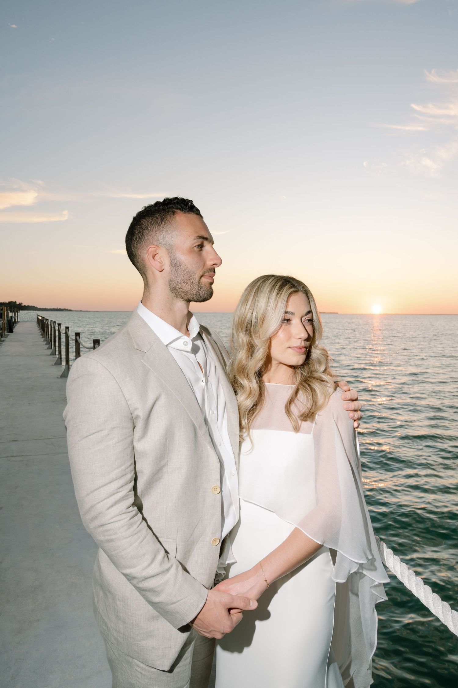 Romantic sunset beach portrait with ocean waves and pier in the background.