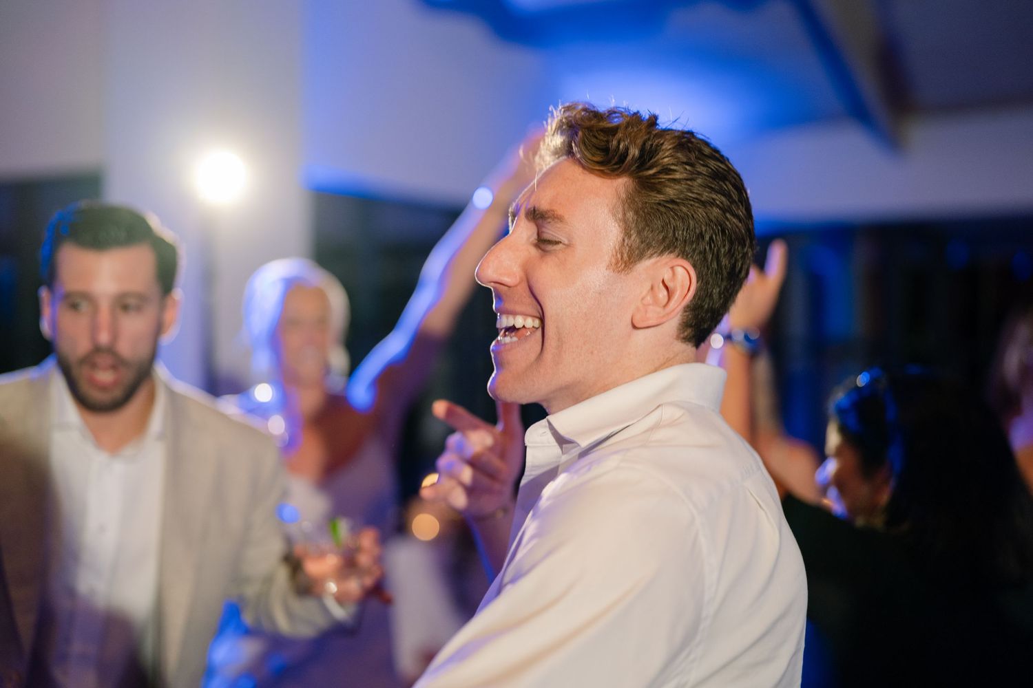 Wedding reception dance floor with blue lighting and guests celebrating.
