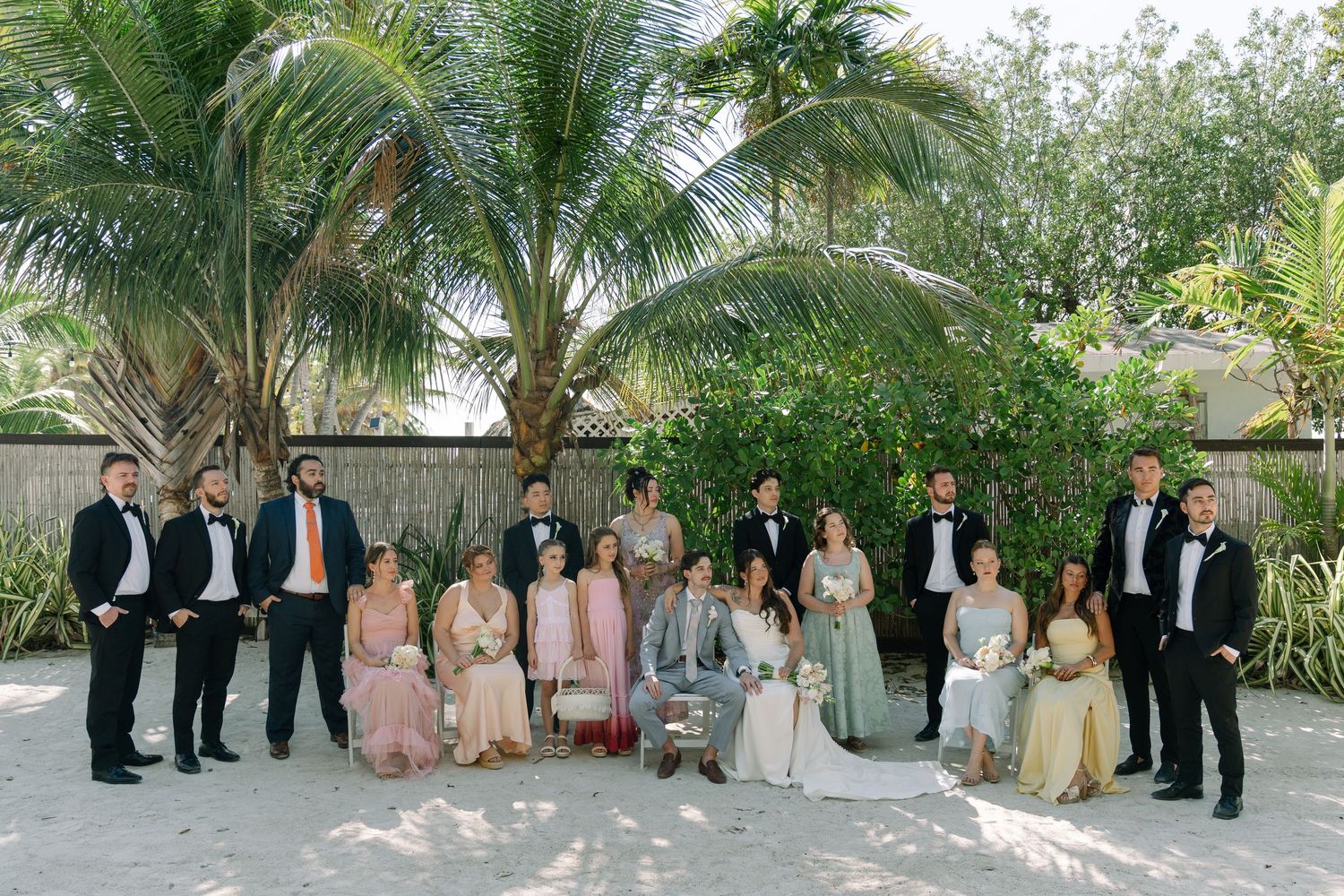 The image shows a group of people in formal attire posing for a wedding or event photo.