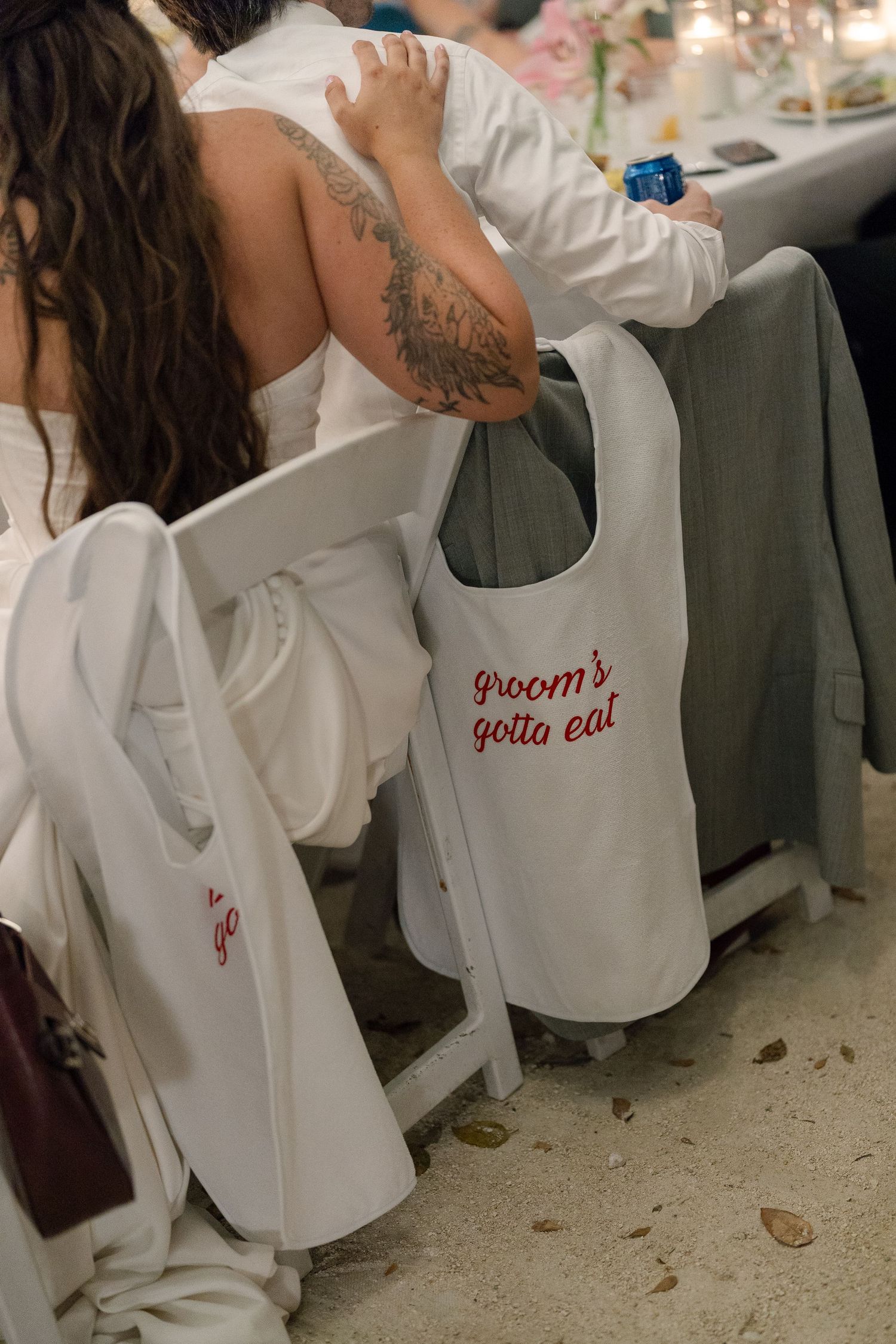 A close-up view of a woman's tattooed arm as she holds a drink at a wedding or event.