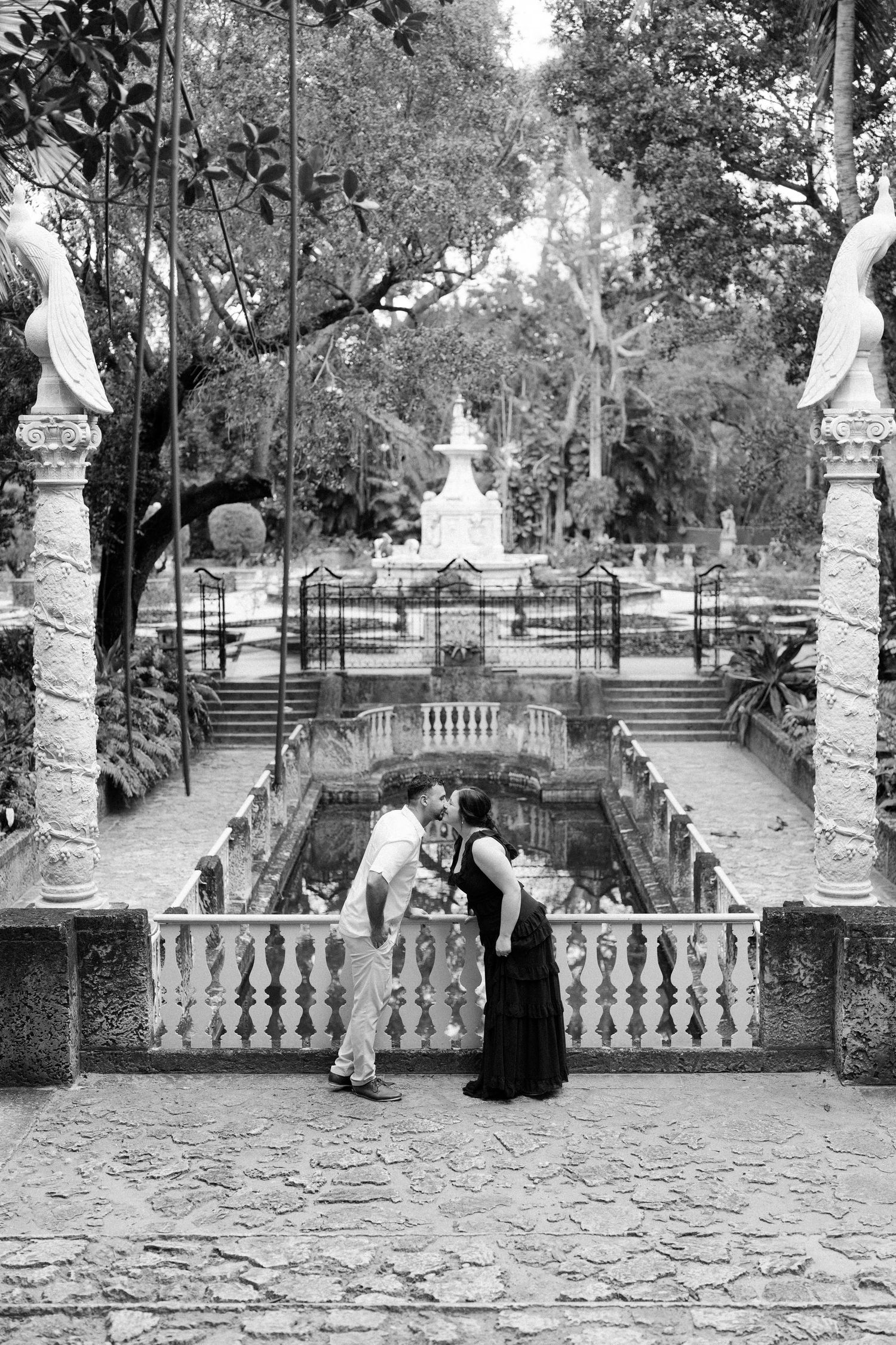 A black and white photo series showing figures seated on stone steps in a garden with ornate balustrades and statues.