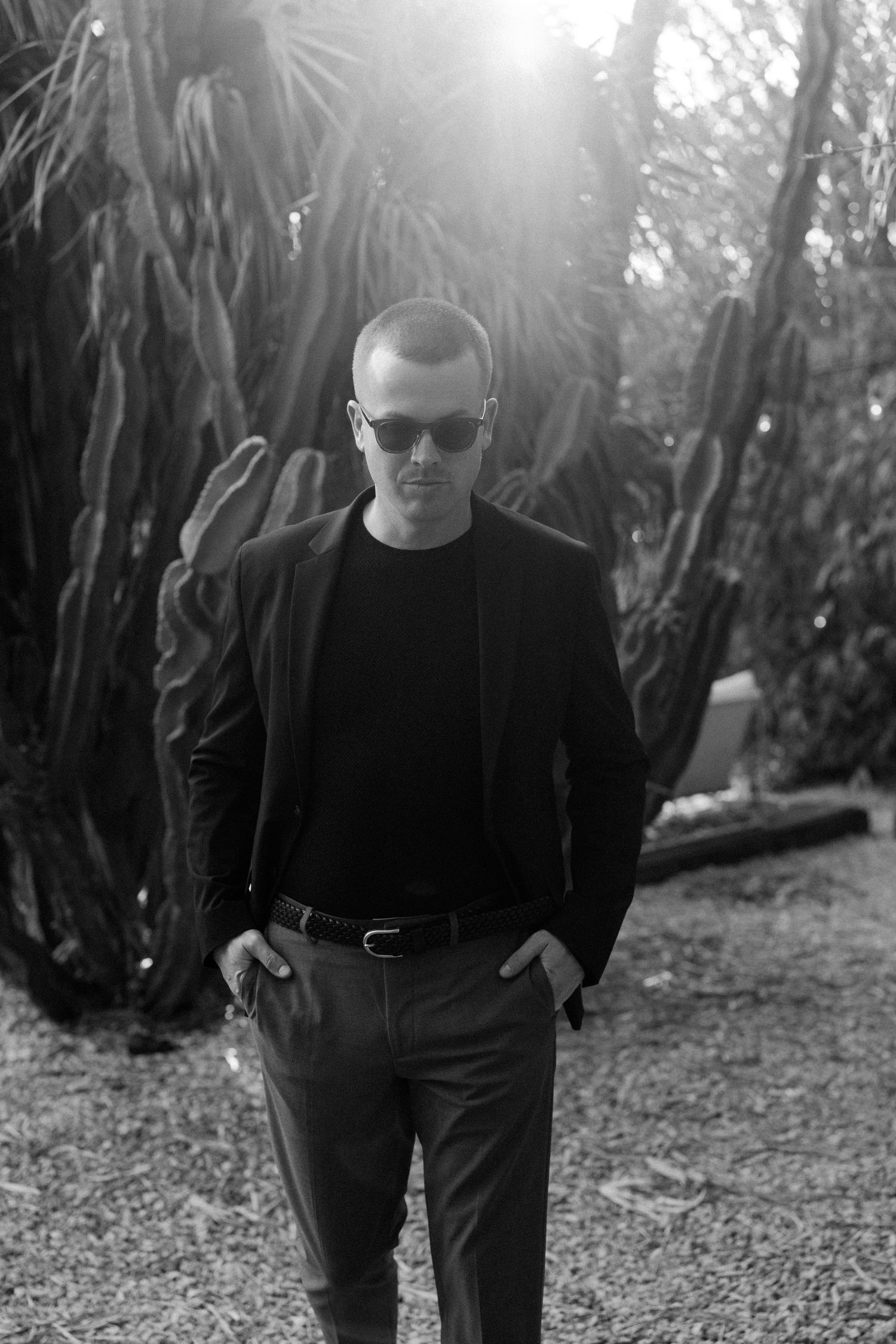 Person in black attire walking through a bamboo garden path in dramatic lighting.