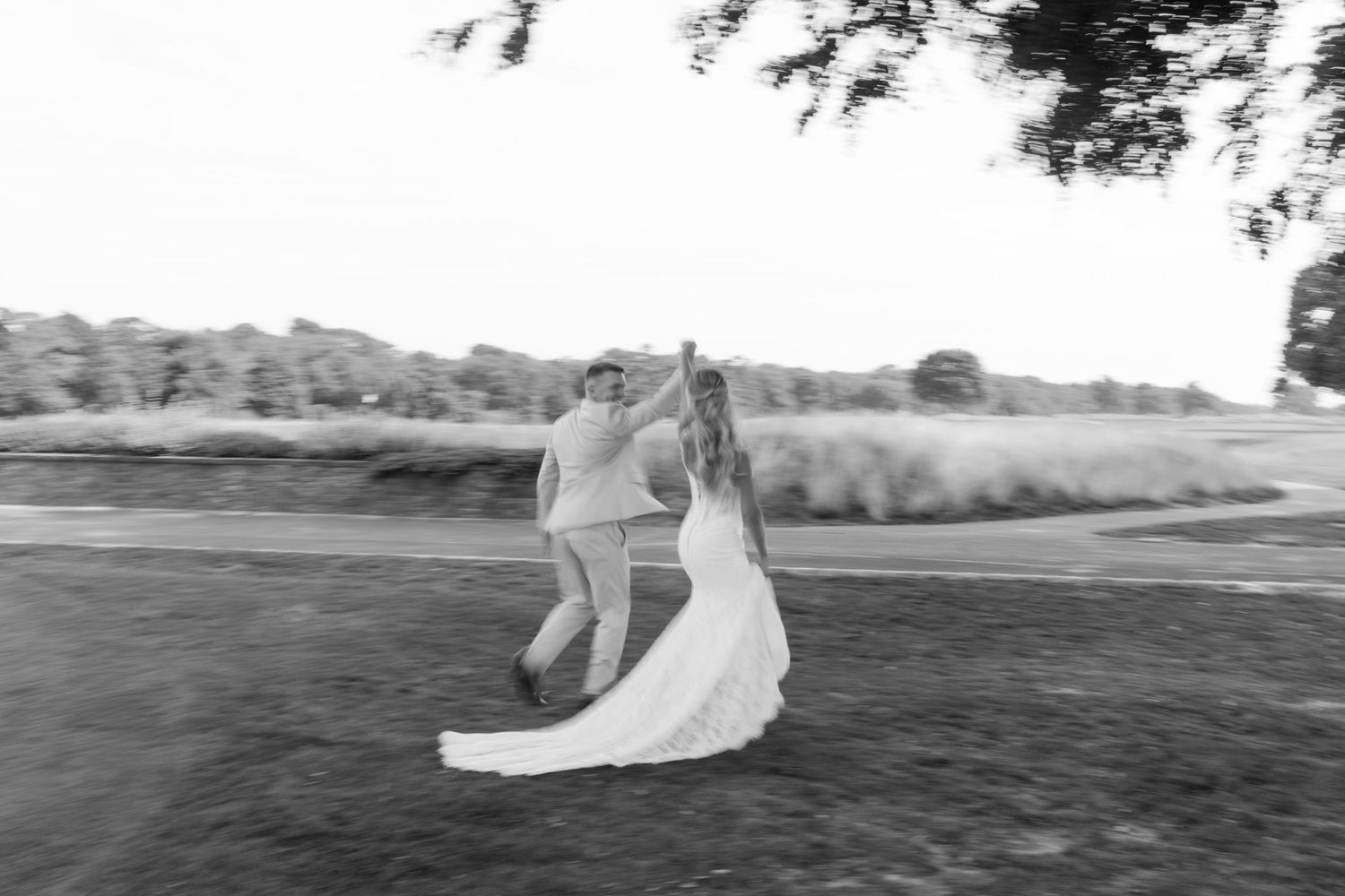 Black and white photo of bride and groom dancing outdoors on their wedding day.