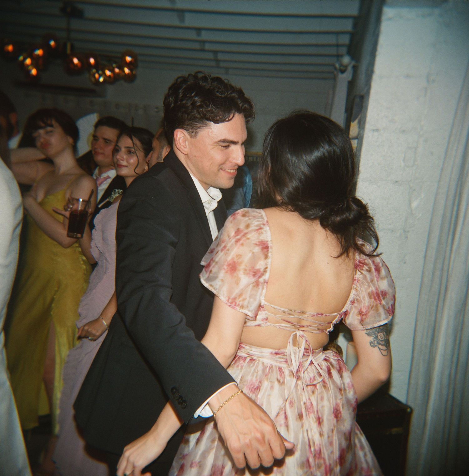 Couple dances closely at wedding reception, woman in floral backless dress, man in black suit.