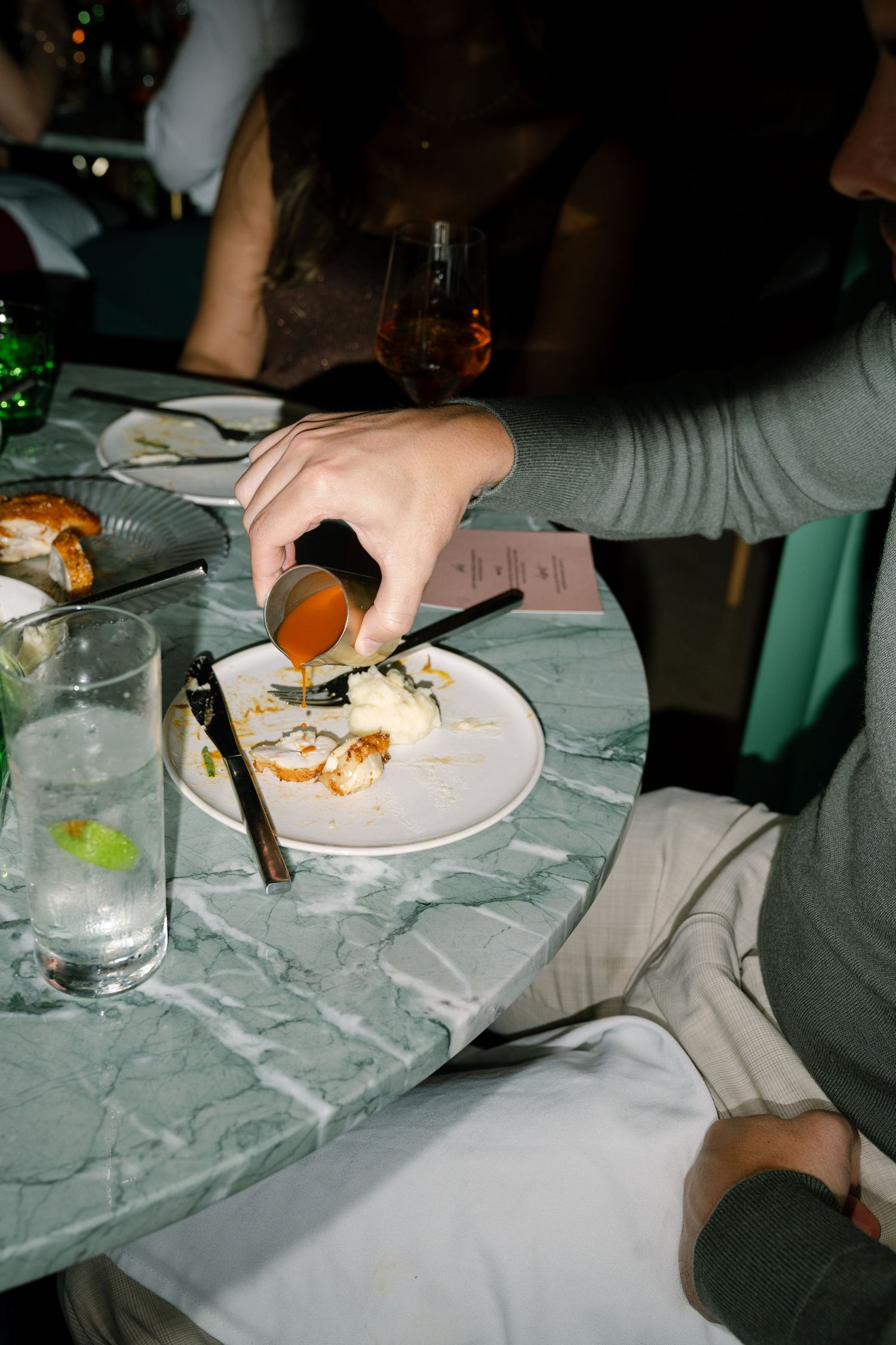 Dinner plates and glasses on a textured gray tablecloth at an evening event.