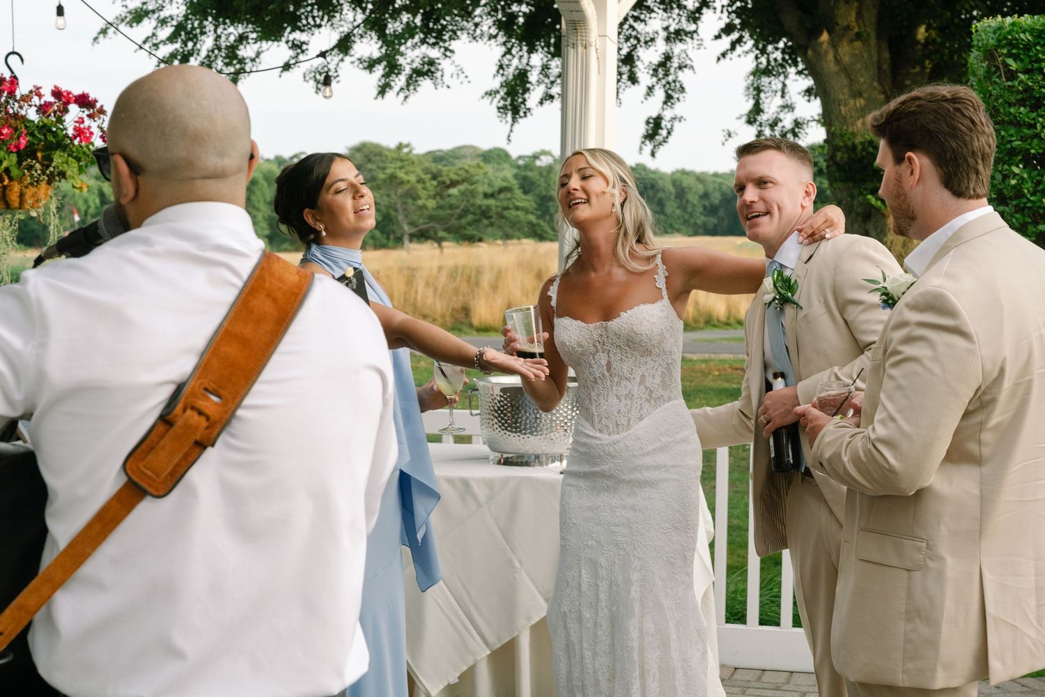 Bride and groom celebrate with guests outdoors at elegant wedding reception venue surrounded by lush greenery.