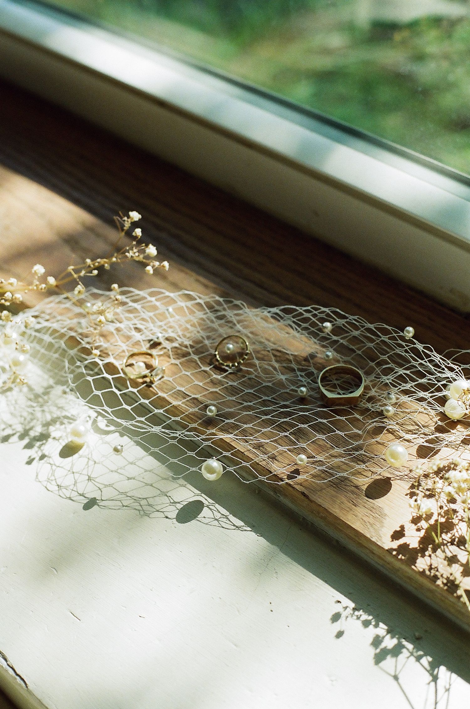 Delicate lace fabric with small white flowers laid across a wooden windowsill in natural light.