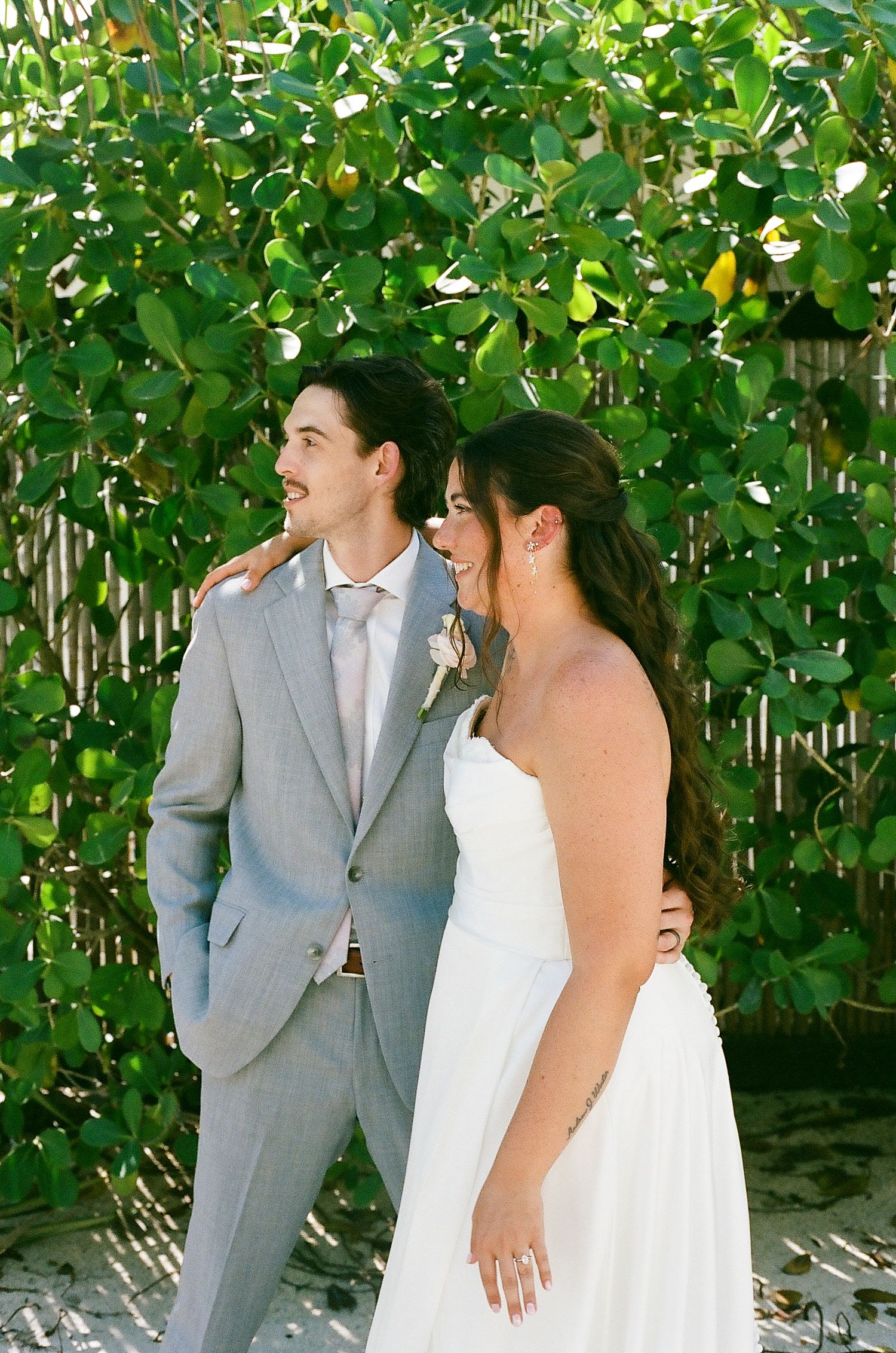 A bride and groom standing together in a garden with lush greenery in the background.