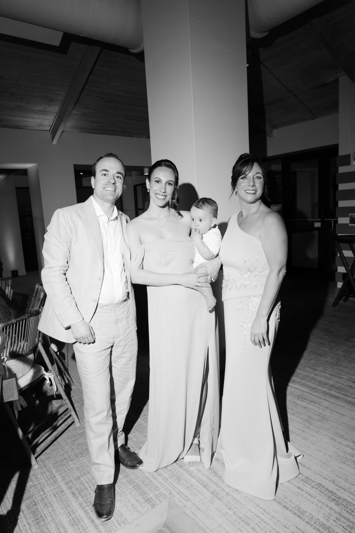 Black and white photo of wedding guests in formal attire dancing and celebrating at a reception.
