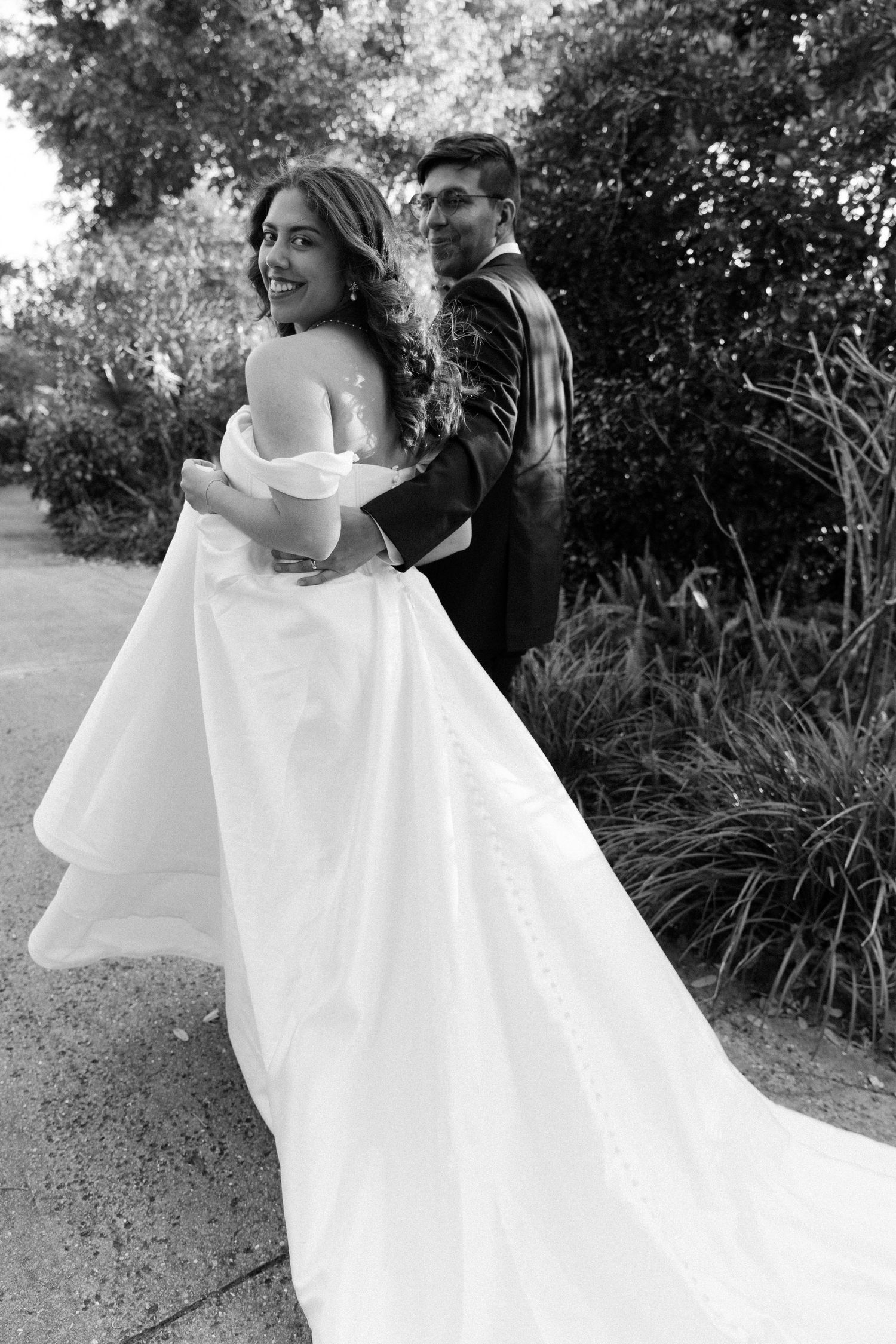 A romantic black and white photo sequence showing a couple twirling and embracing in formal wedding attire outdoors.