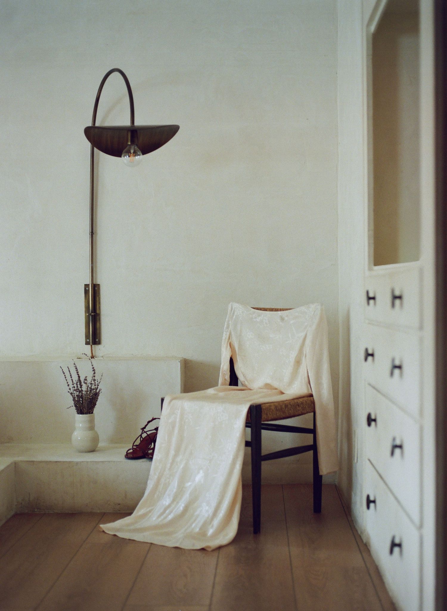 Minimalist interior scene with white walls, wooden floor, and scattered furniture creating a serene atmosphere.