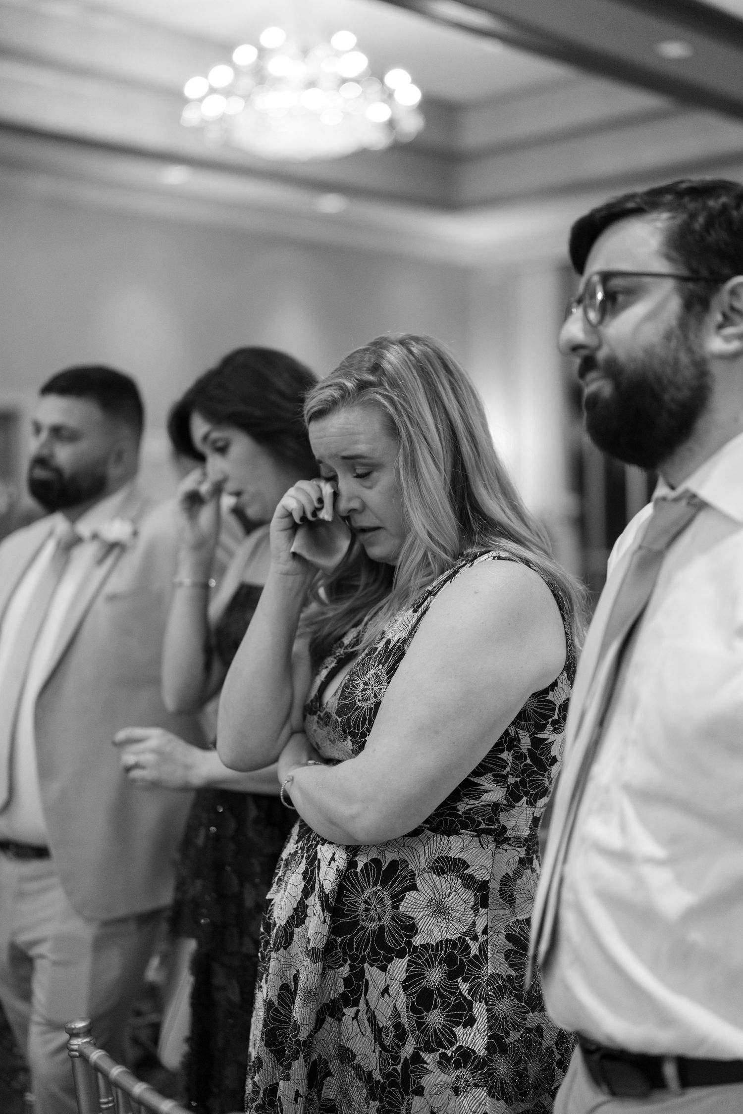 Wedding guests wiping tears during an emotional ceremony moment.
