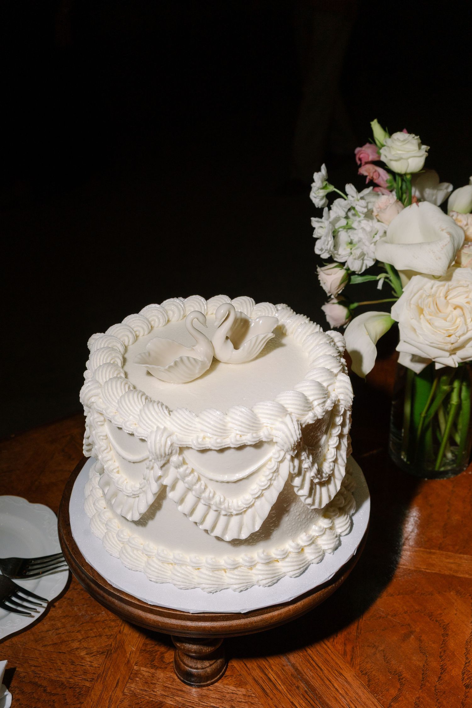 A beautifully decorated white wedding cake with intricate frosting designs and a bouquet of white flowers beside it.