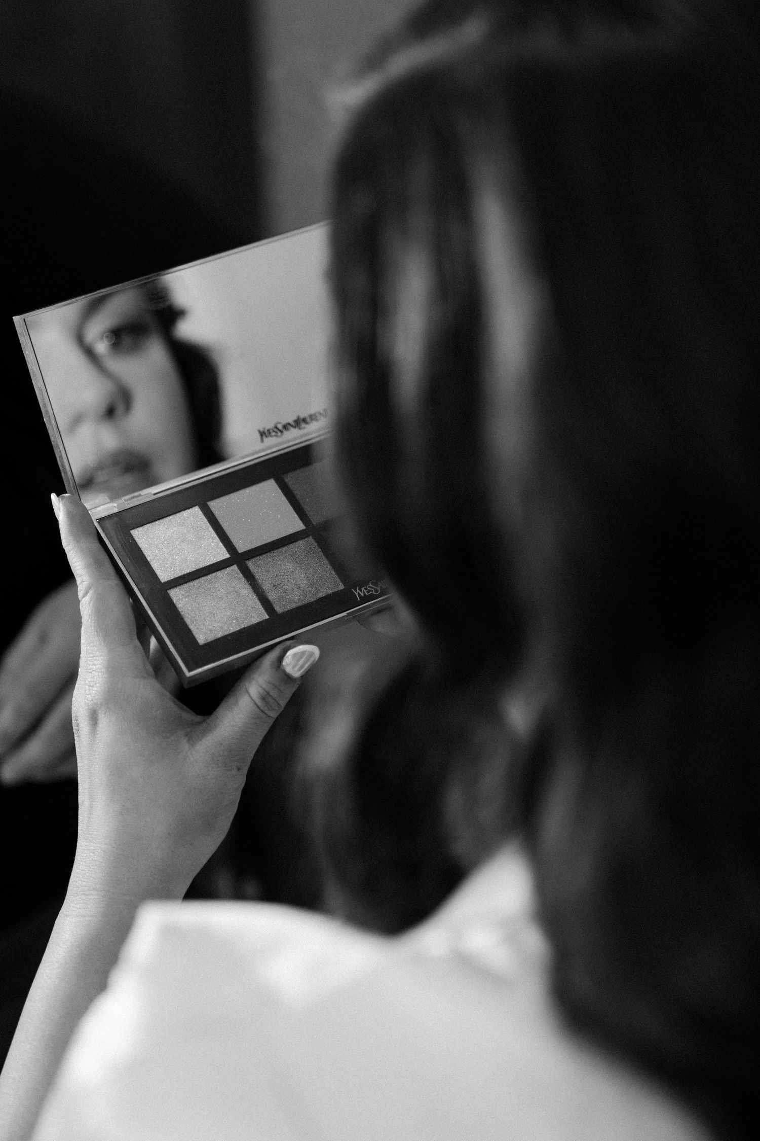 A woman holds a makeup palette in a black and white image.