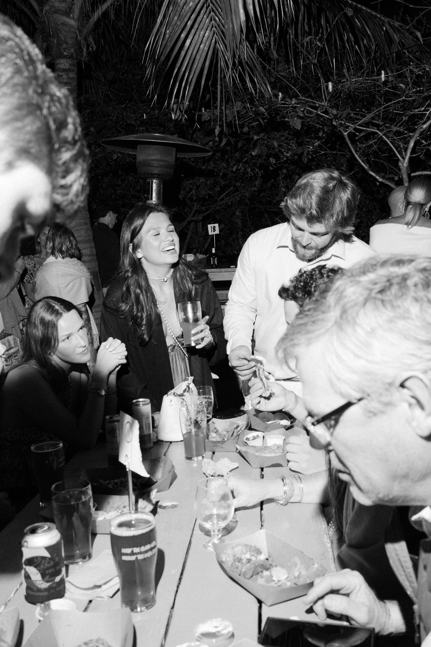 Group of people gathered around a table at an outdoor nighttime party.