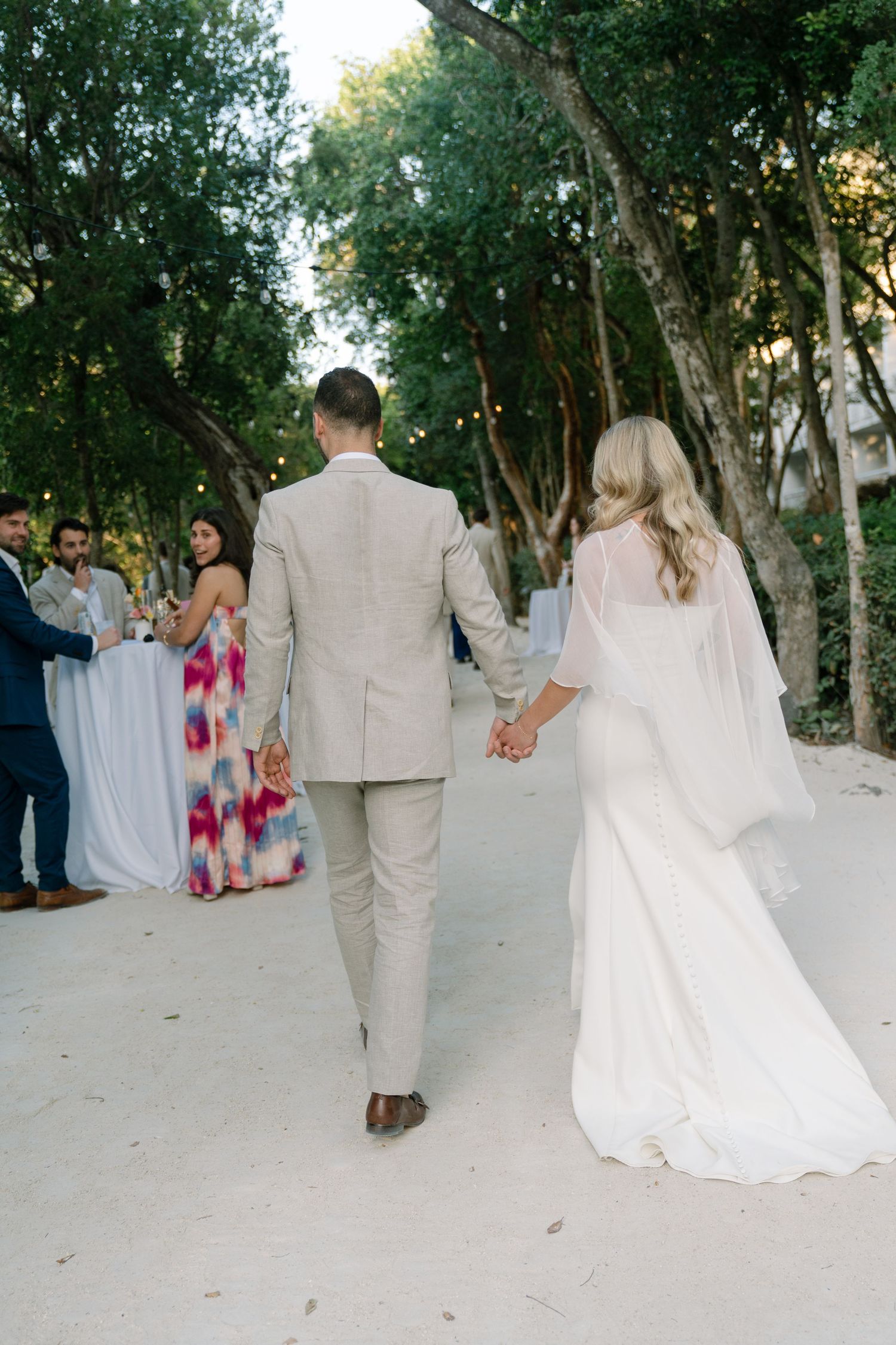 Wedding party walking along a tree-lined path in formal attire.