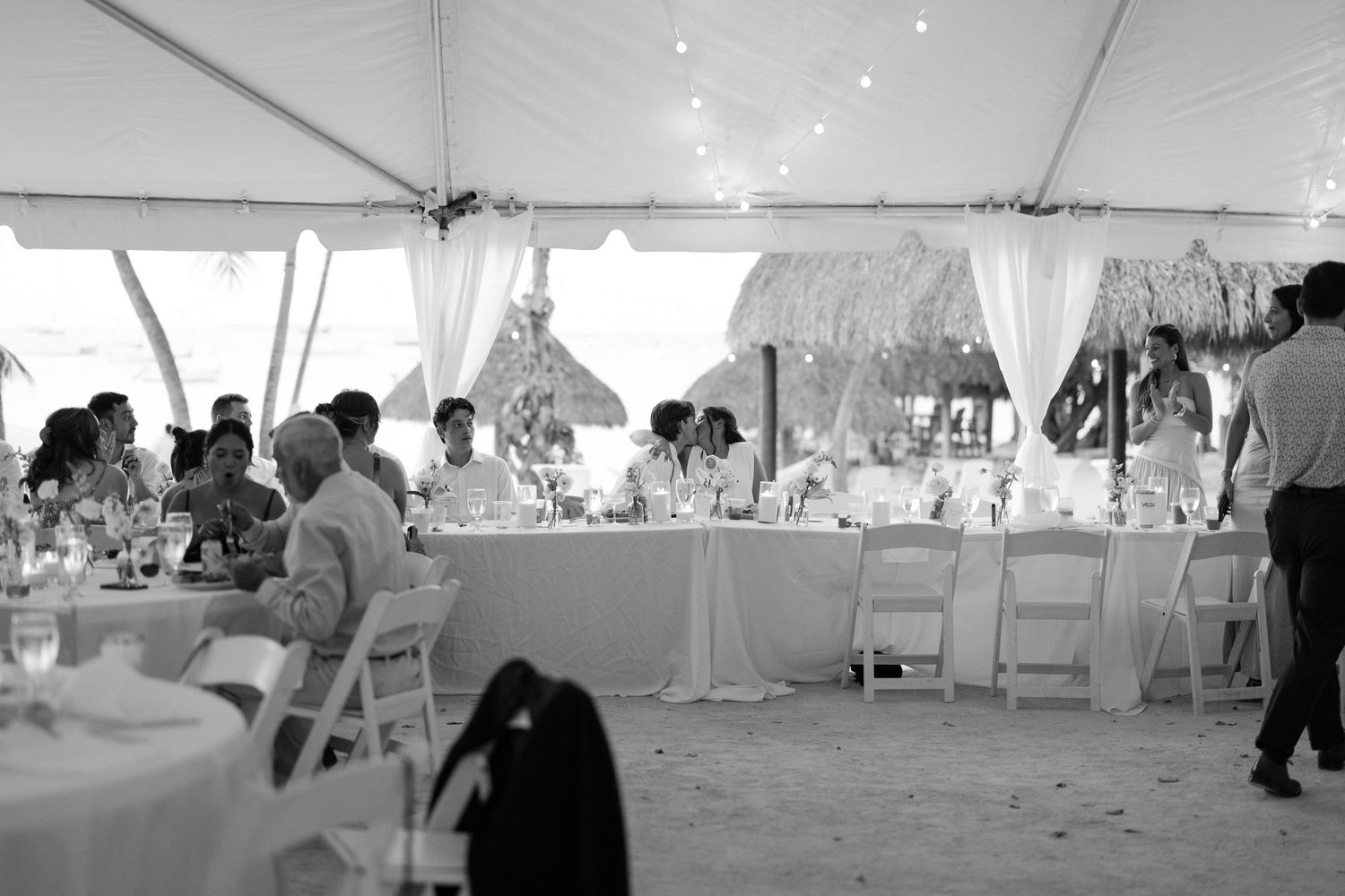 Interior of a white wedding tent with tables and chairs set up for a reception celebration.