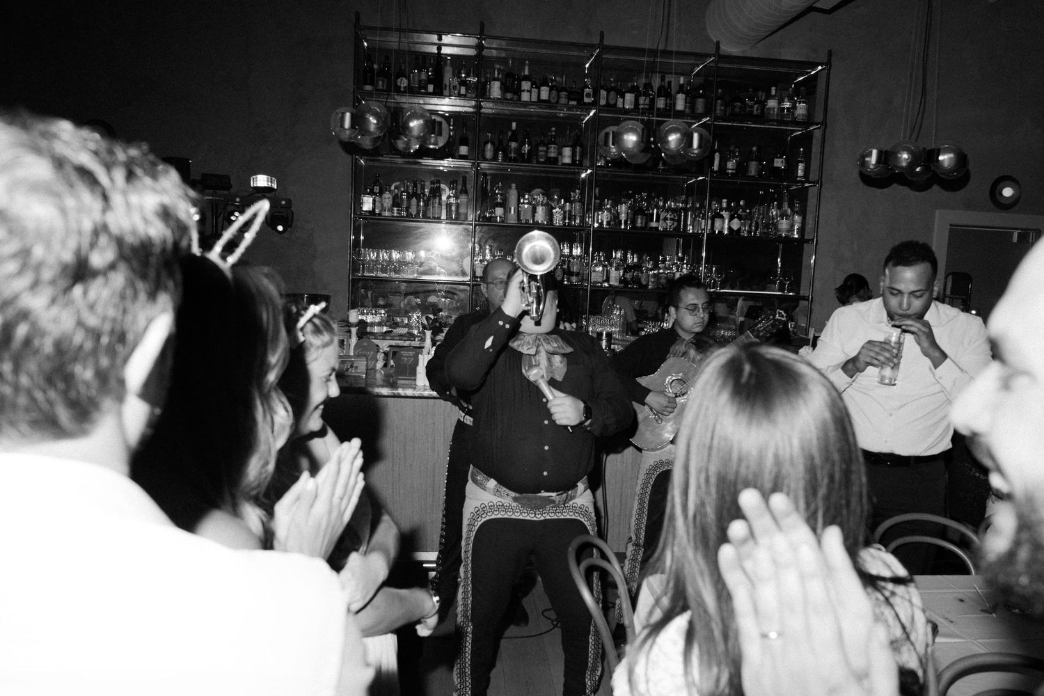 A crowded bar scene in black and white showing patrons gathered in a social setting.