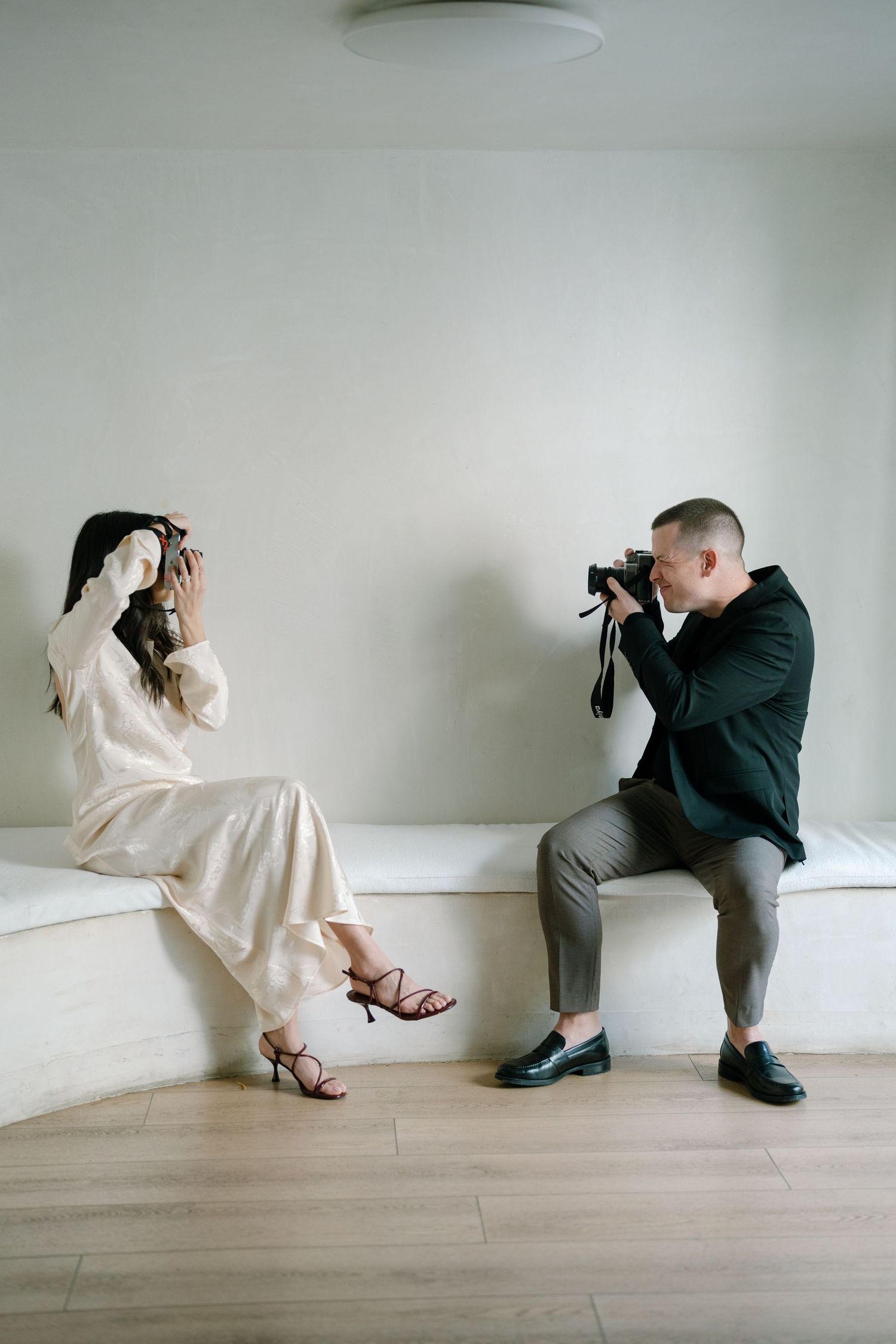 Artistic photo series of two people in contrasting outfits posing against a white wall.