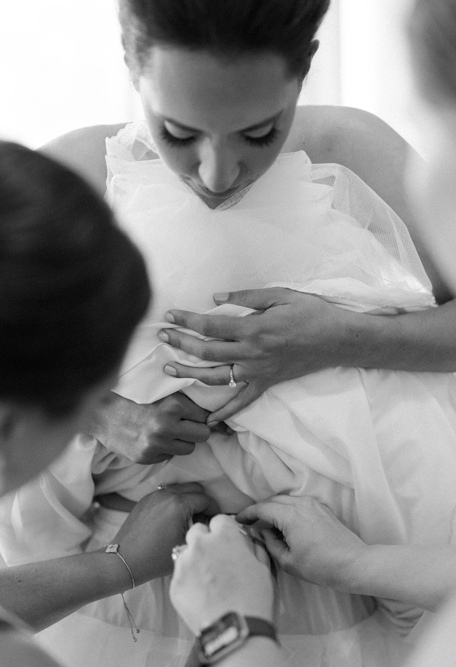 A series of black and white photos showing hands delicately holding and examining white fabric.
