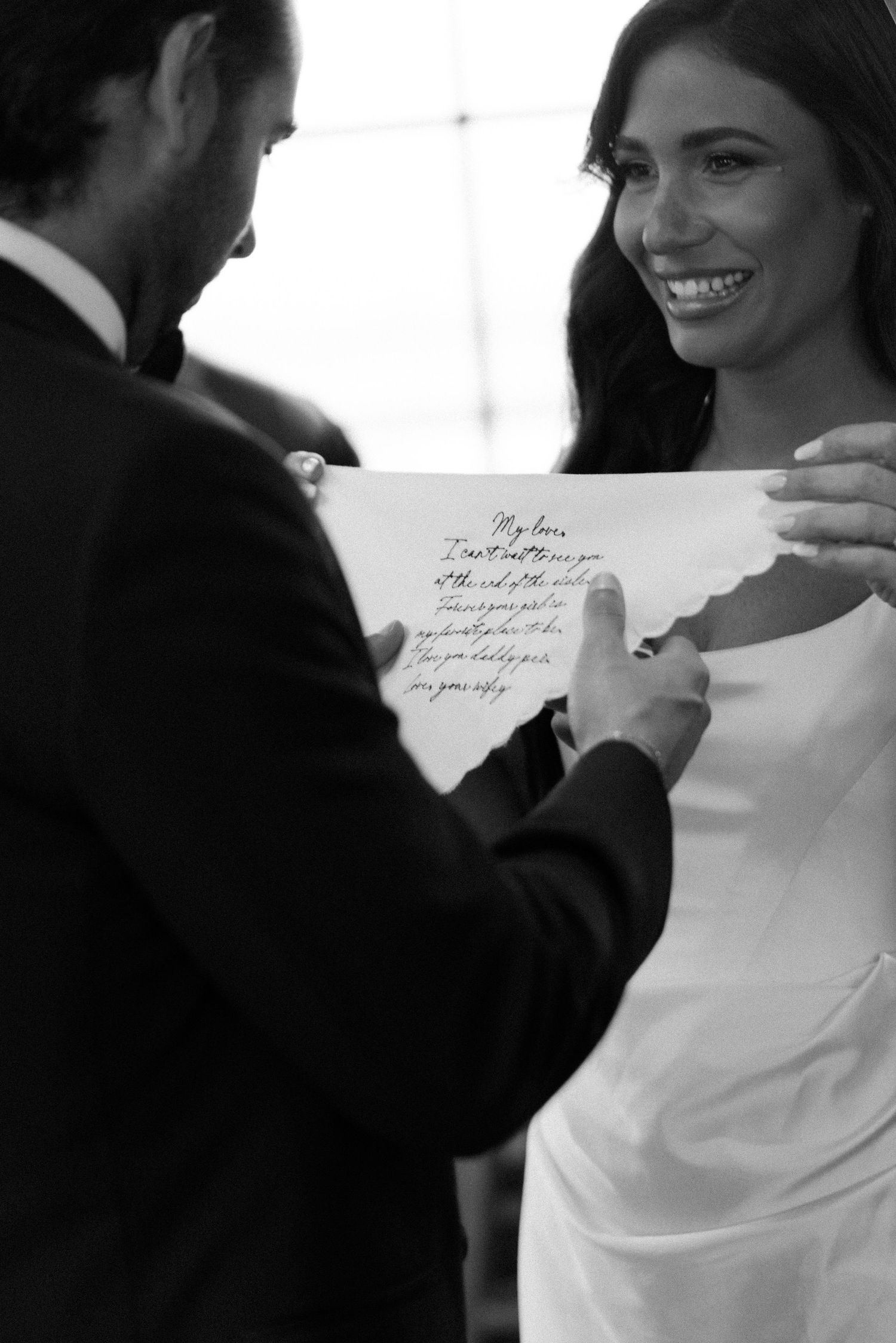 A couple shares a heartfelt moment reading a handwritten note together at their wedding celebration.