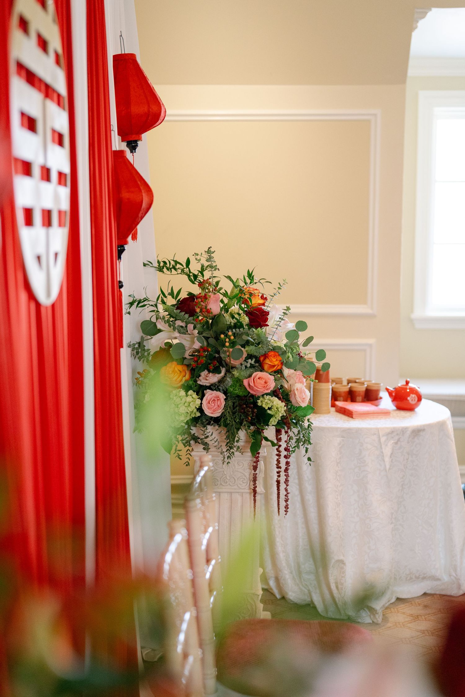 Elegant wedding reception tables with red curtains and floral centerpieces.