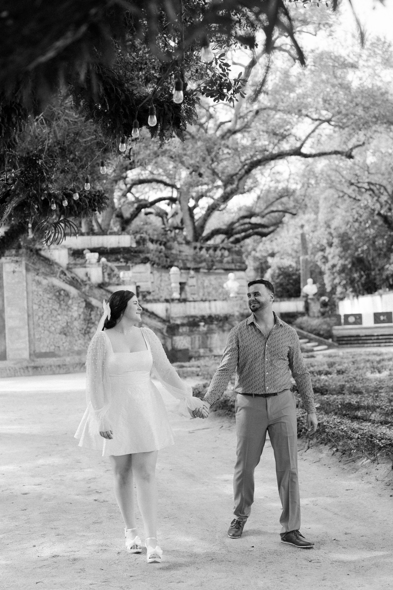 A sequence of vintage black and white photos showing people walking and interacting in a park-like setting under large trees.