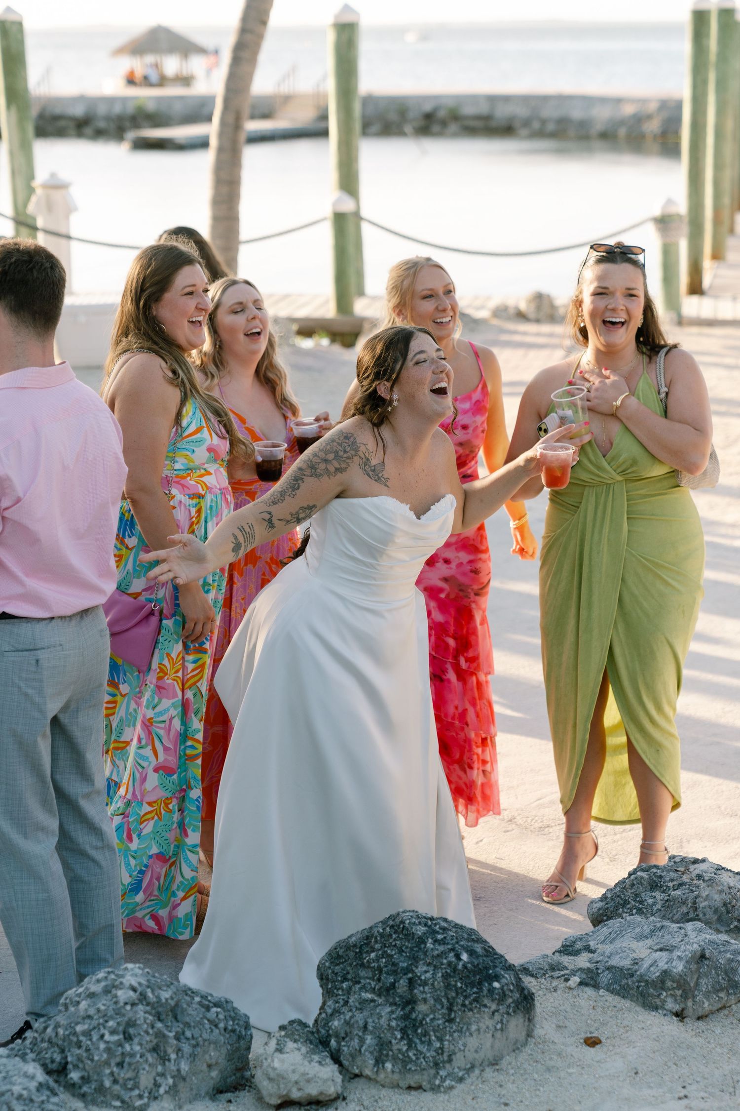 A group of women in colorful dresses are celebrating together on a beach.