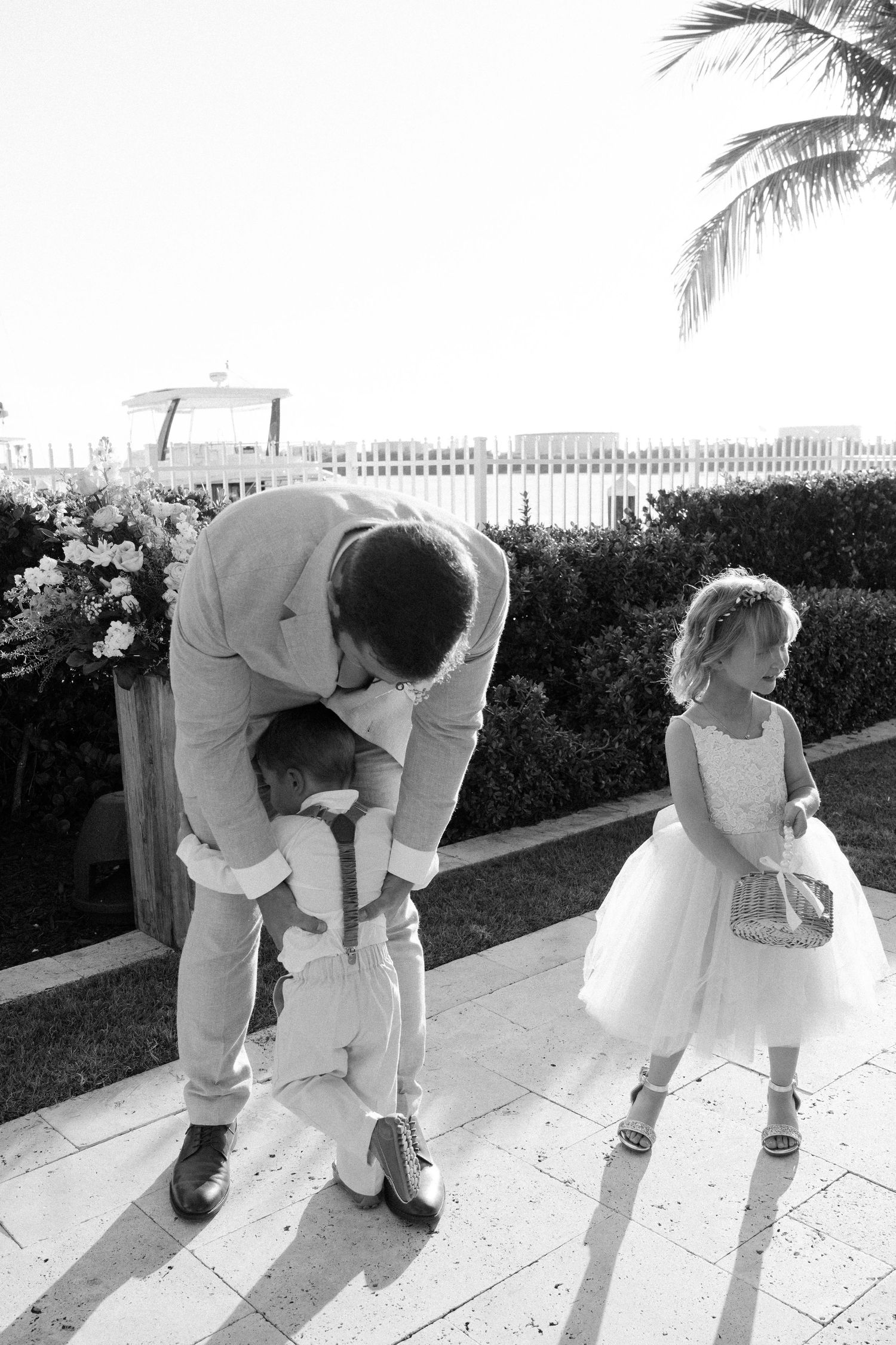 Series of black and white photos showing playful moments between wedding guests on a sunny patio.