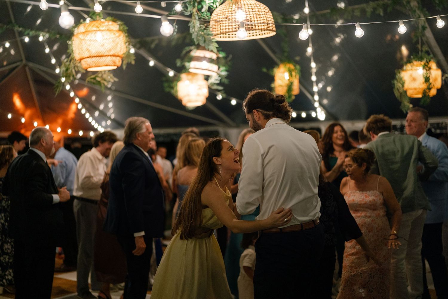 Couples dancing under warm string lights and wicker lanterns at a romantic wedding reception.