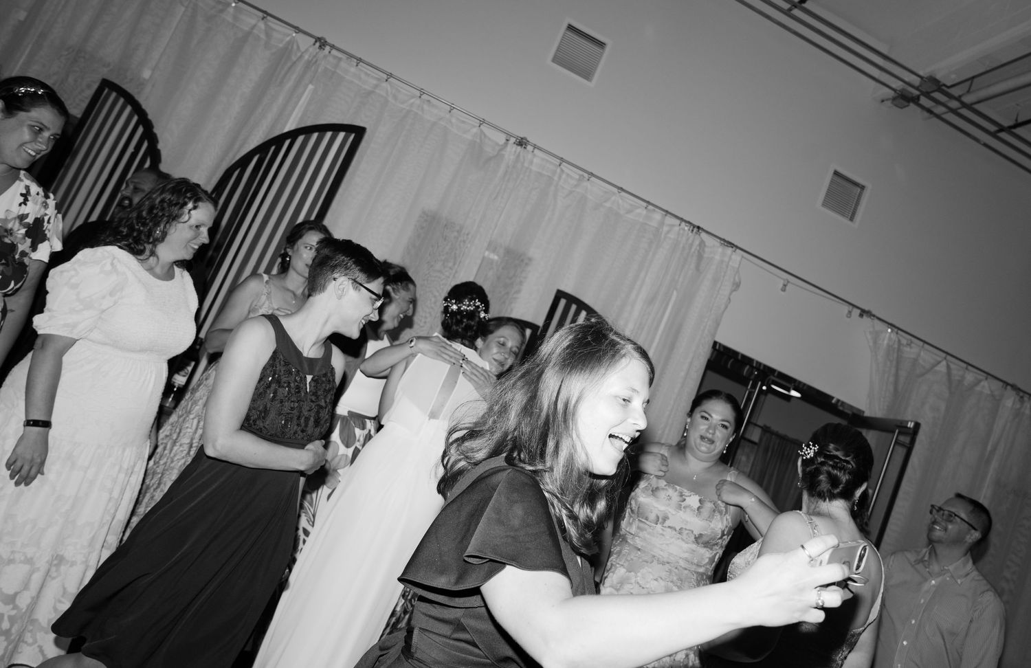 Black and white photo showing dancers in motion at a lively dance hall with vintage furnishings.