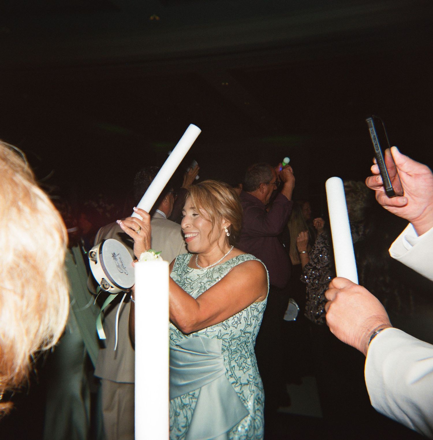 Wedding reception dance floor scene with guests dancing in dim lighting.
