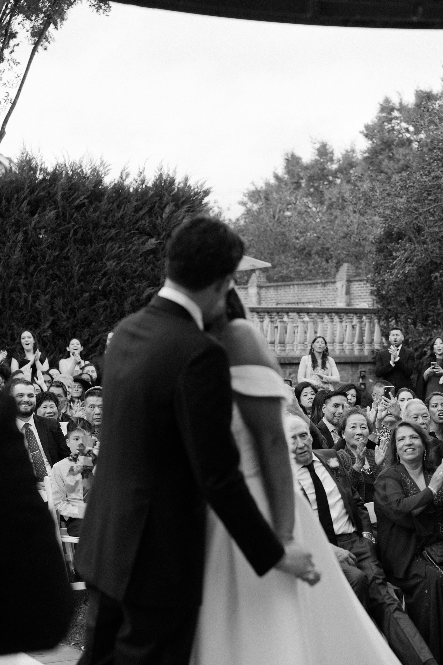 Wedding celebration crowd reacting with joy during outdoor ceremony.