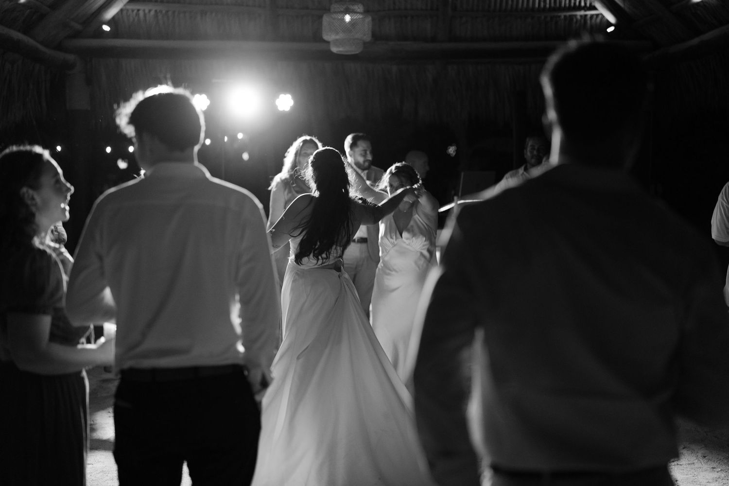 A black and white image of a bride and groom dancing at their wedding reception under the stage lights.